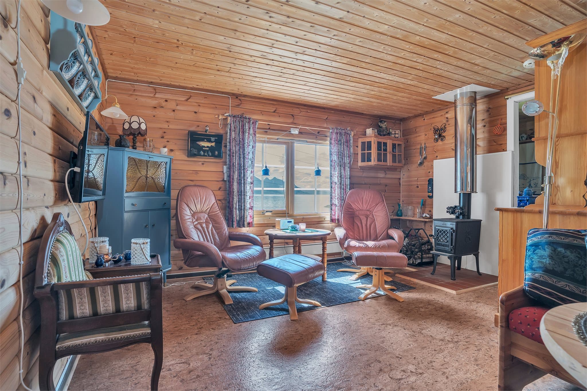 Stuen varmes opp av en vedovn plassert på keramiske fliser.