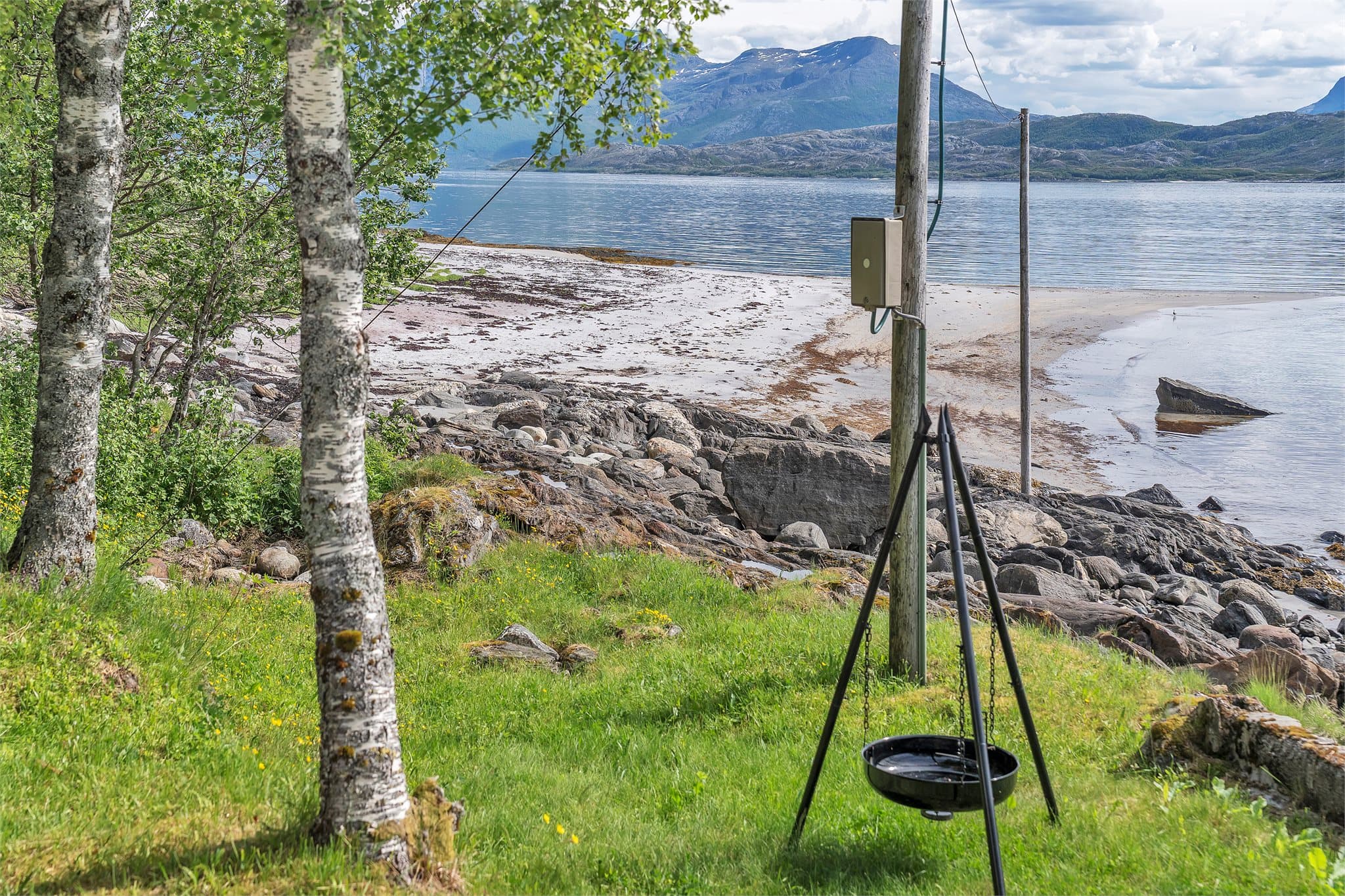 Tomten skråner ned mot havet og er opparbeidet med plen rundt hytta.