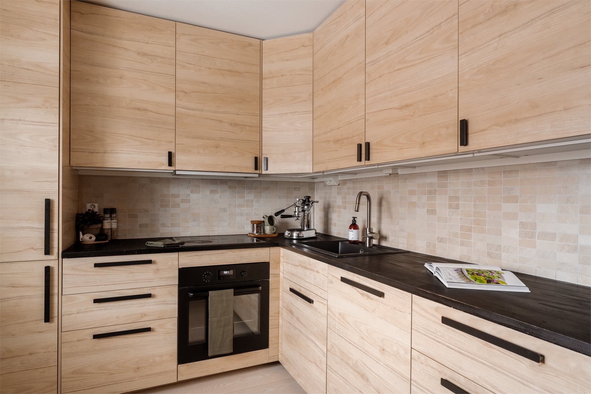 Kjøkkeninnredning med glatte fronter, heltre benkeplate med nedfelt kum. Induksjonstopp, stekeovn, oppvaskmaskin og kjøl/frys er integrert iinnredningen.