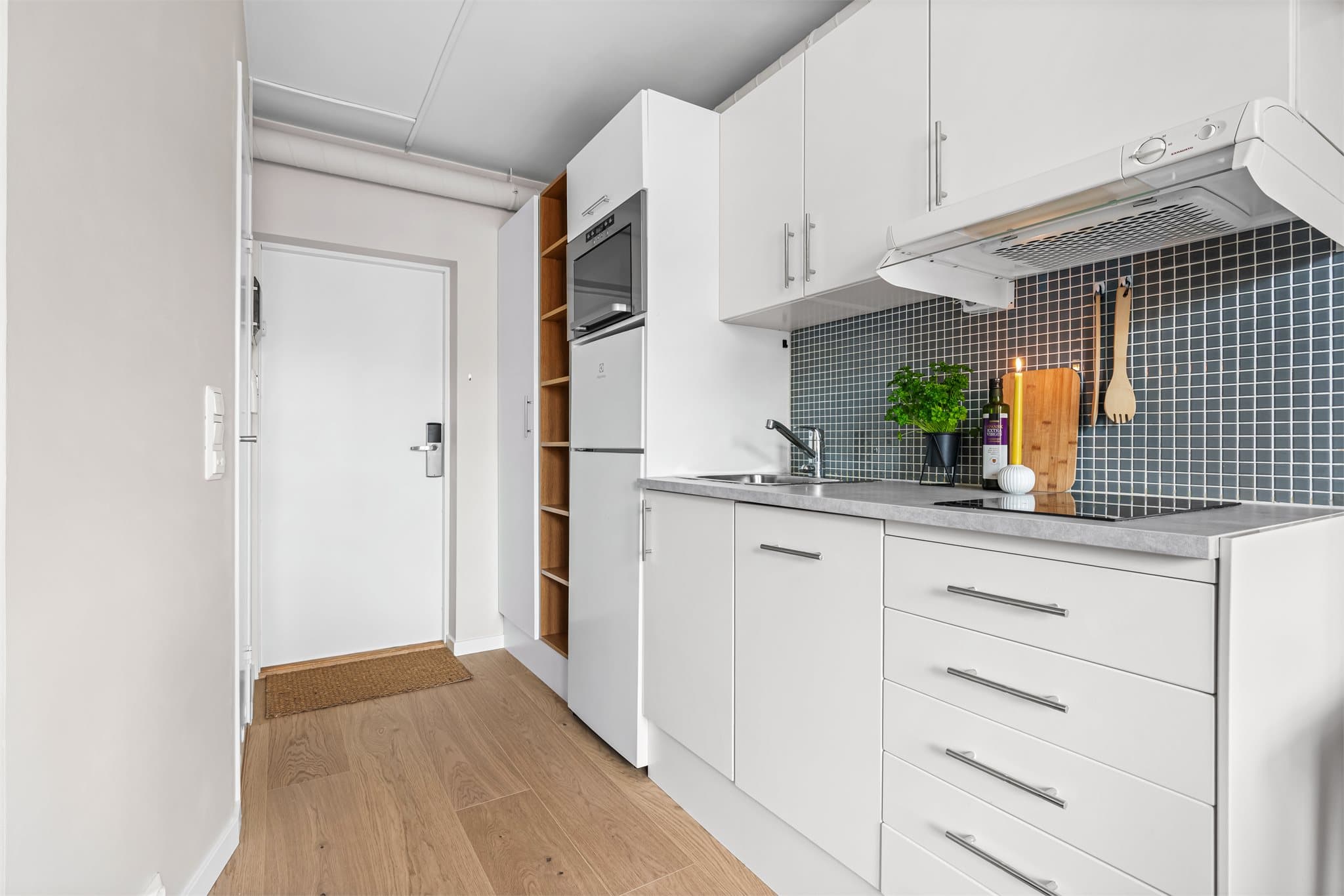 Kjøkkeninnredningen har glatte fronter og en praktisk laminatbenkeplate. Flisene over benken beskytter veggen.