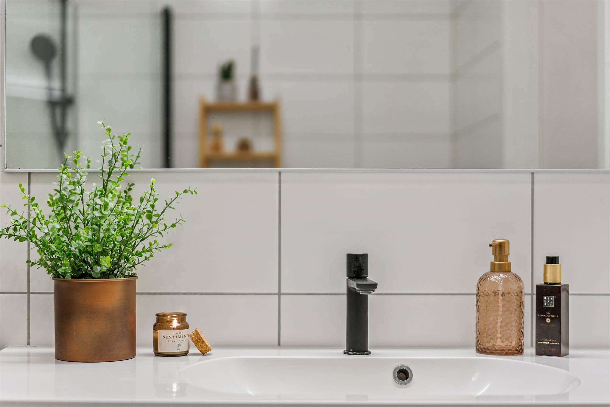 Badet er innredet med dusjhjørne, helservant på vegghengt skuffeseksjon og klosett.