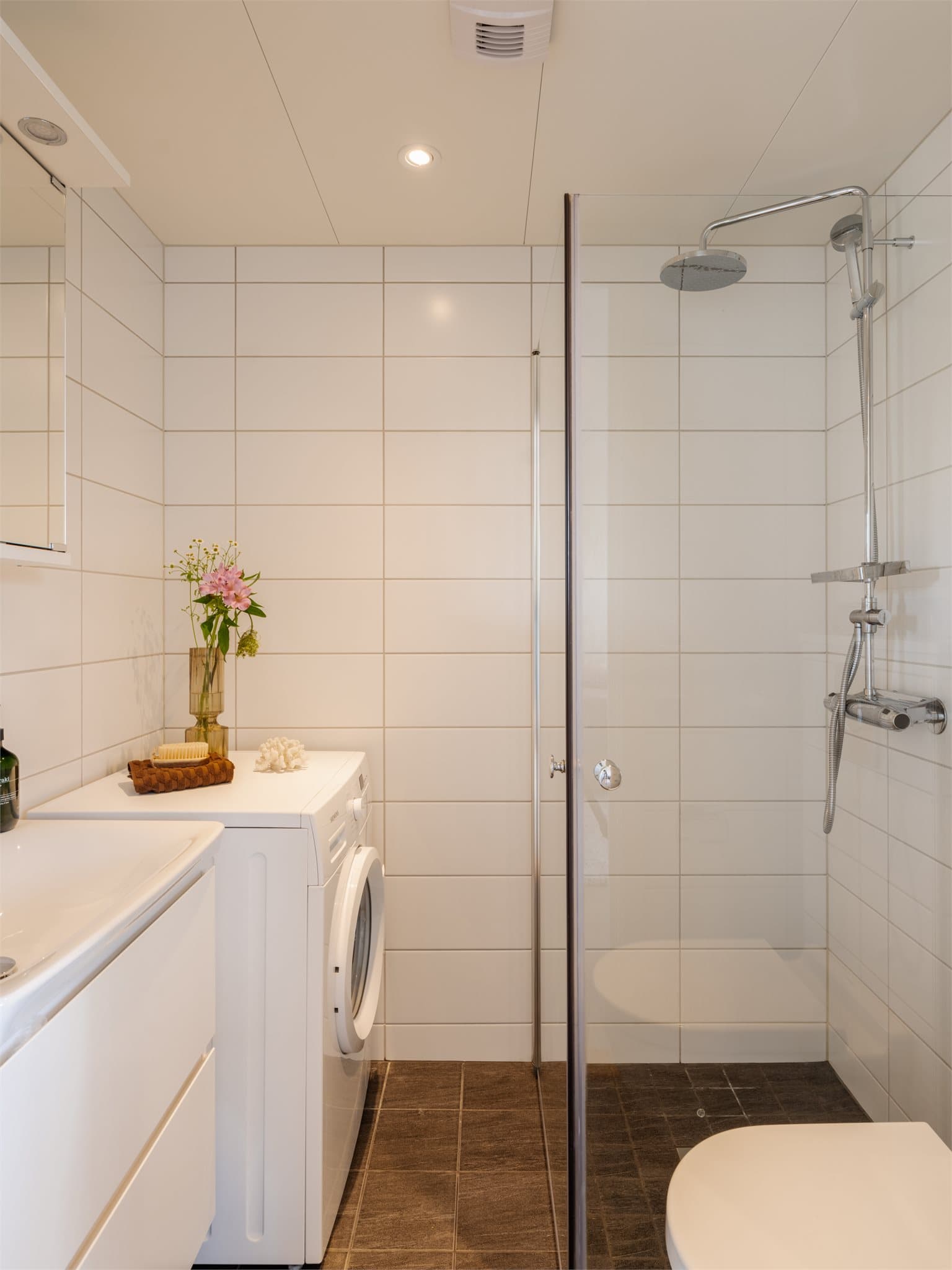 Bad med flislagte overflater, gulvvarme, vegghengt klosett og opplegg for vaskemaskin.