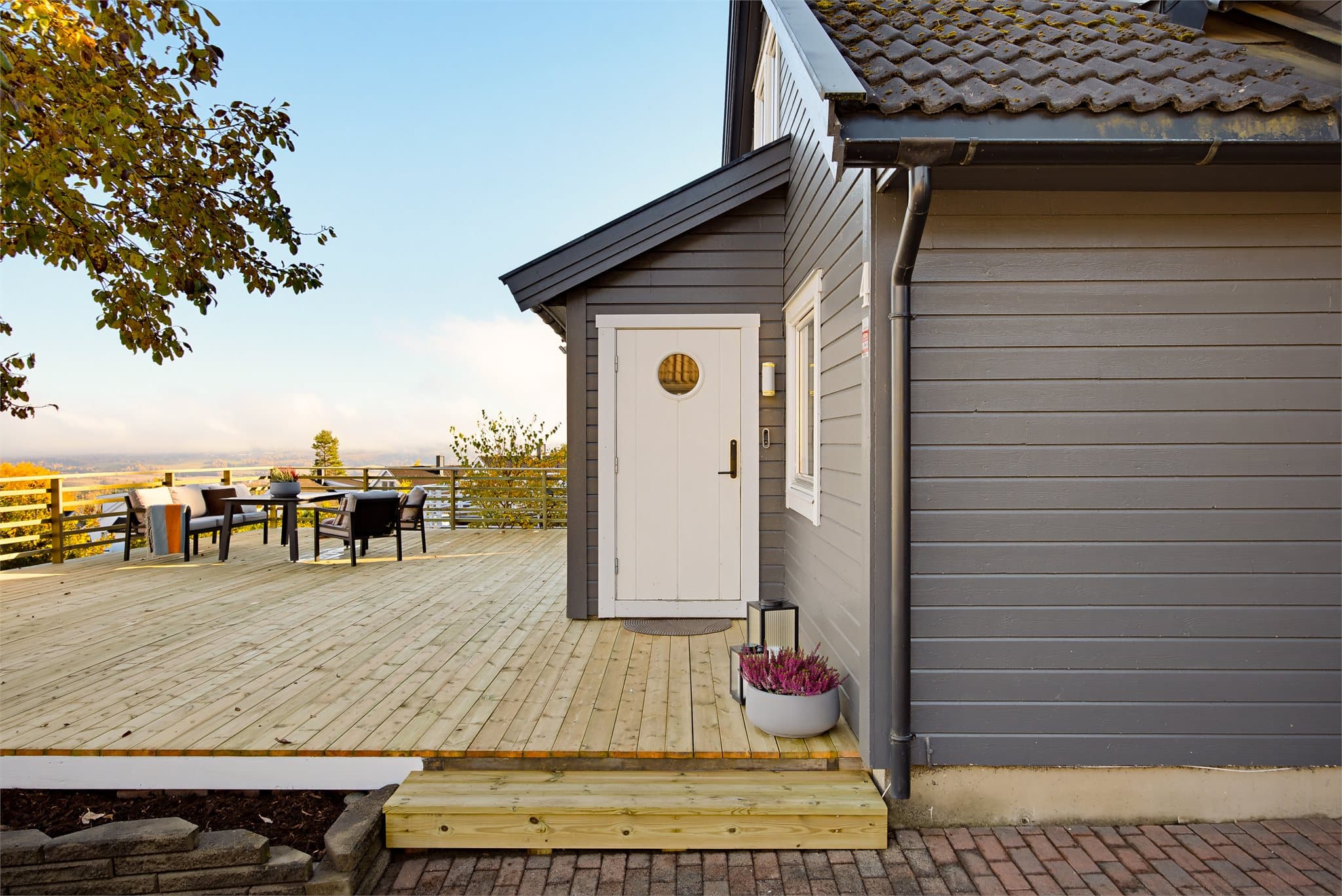 Boligen har et innbydende inngangsparti, med stor terrasse foran inngangsdøren.