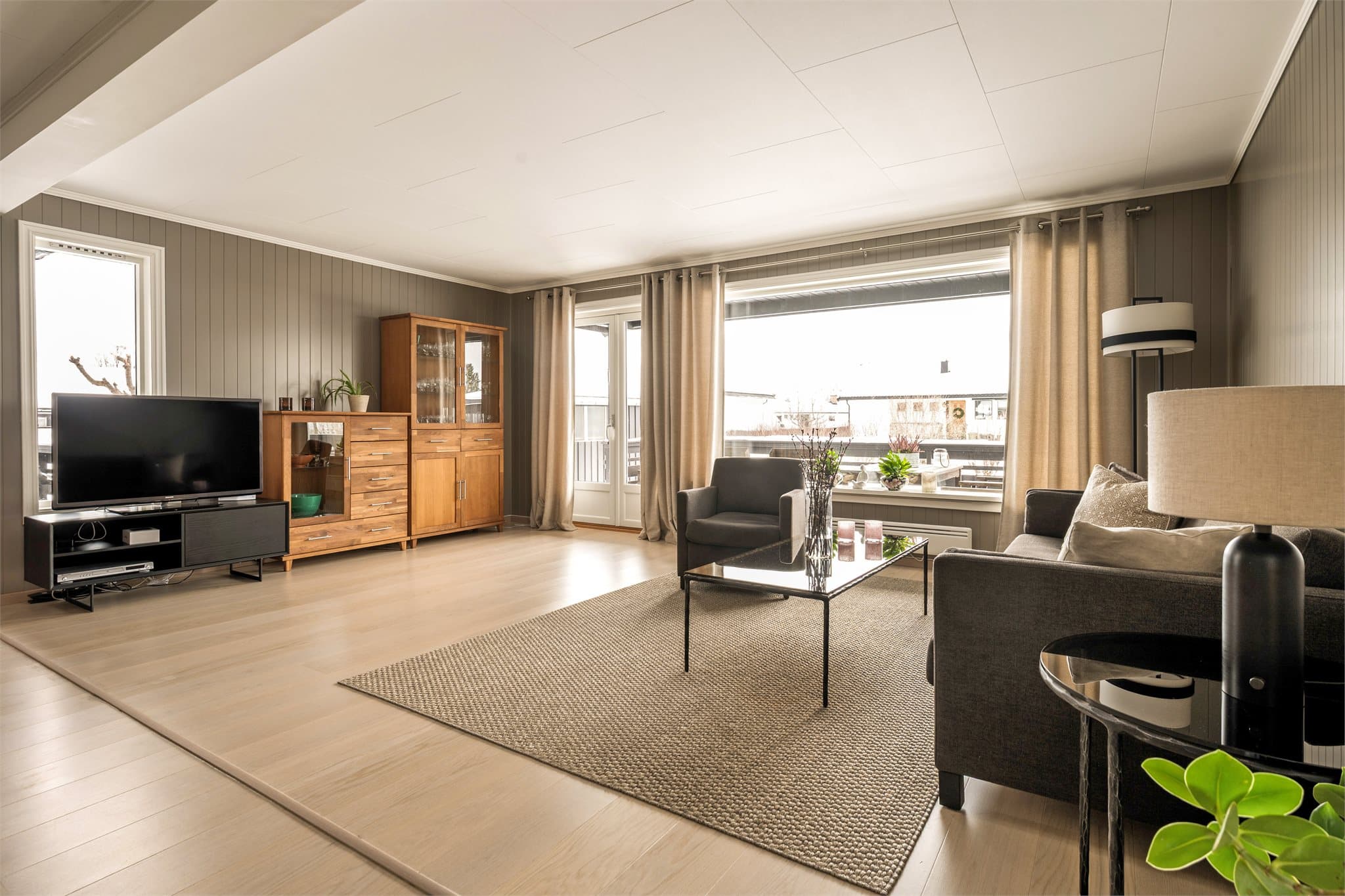 De store stuevinduene slipper inn rikelig med naturlig lys og gir rommet en åpen og levende karakter gjennom hele dagen. Her strømmer solen inn og fremhever de lyse flatene, samtidig som utsynet gir en fin kontakt med uteområdet.