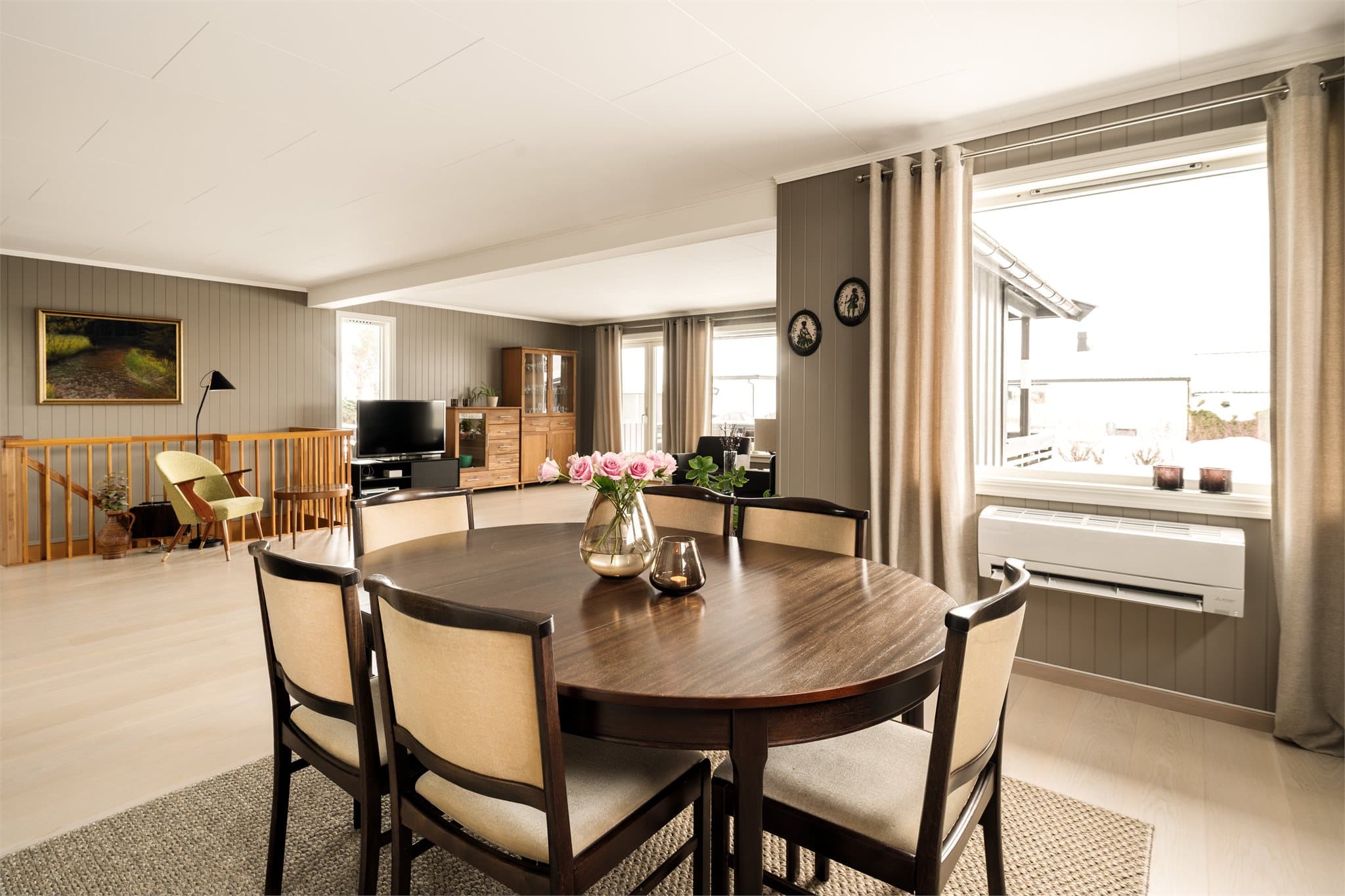 På veggen er det montert varmepumpe i praktisk knehøyde, diskret integrert i rommet. Den sørger for et behagelig inneklima året rundt – kjølende på varme sommerdager og lunende når vinteren melder sin ankomst.