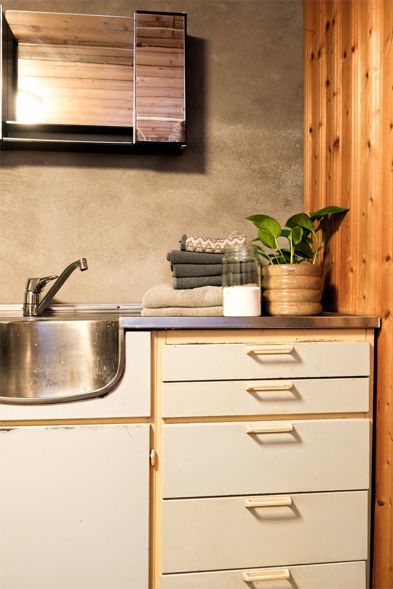 Benkeplaten i stål med solid utslagsvask understreker det praktiske – her er det rom for grovvask, blomsterpotter, maling eller store klesvasker. Den robuste overflaten tåler bruk, og gir et ærlig og funksjonelt preg.