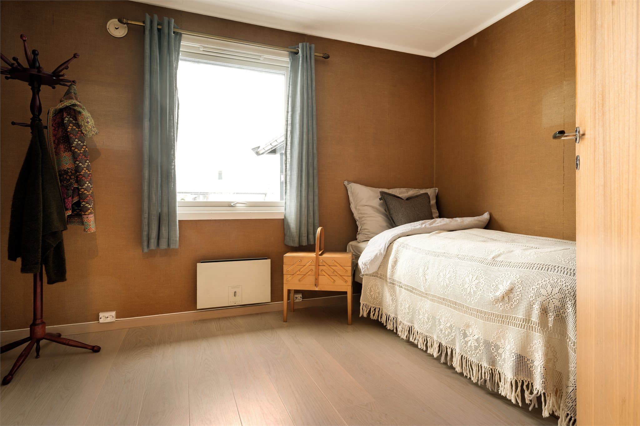 Soverom 3 tar deg rett tilbake til 1970-tallet – på den aller beste måten. Veggene er kledd i mørk, nesten sennepsgul strietapet som gir rommet en dyp og lun karakter.