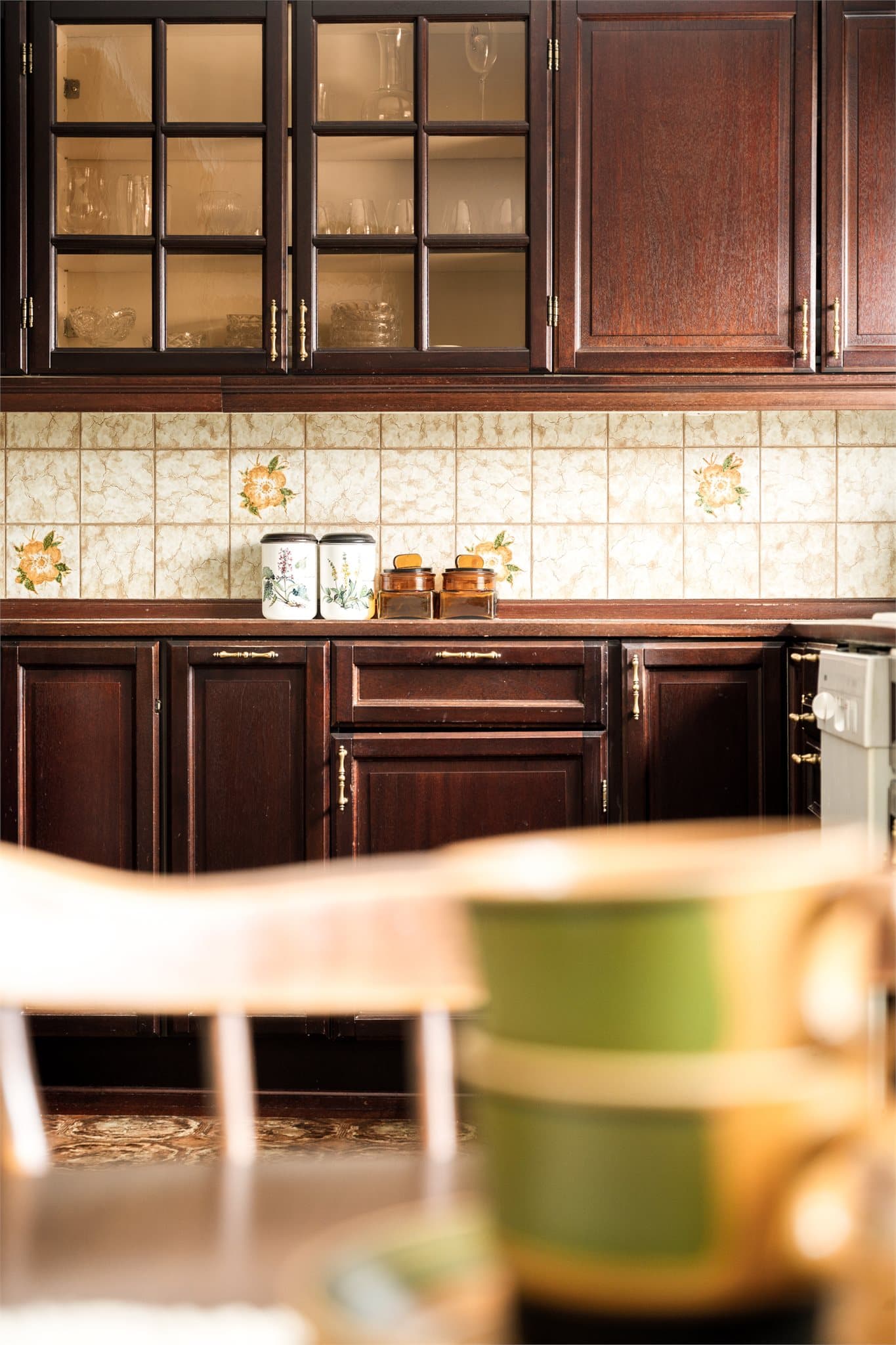 De retroinspirerte flisene, dekorert med blomster i varme gule og myke grønne toner, bringer en leken og sjarmerende energi inn i kjøkkenet.