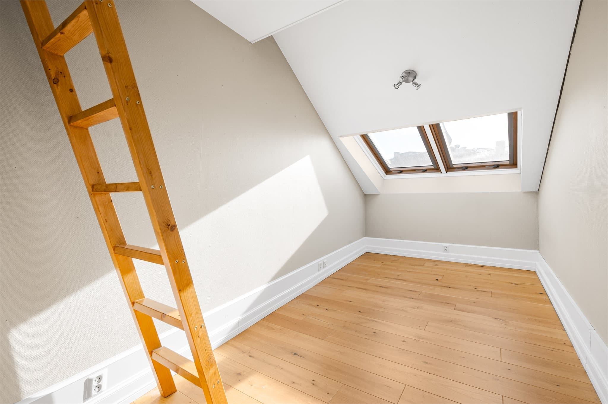 Soverom med skråtak og takvindu.