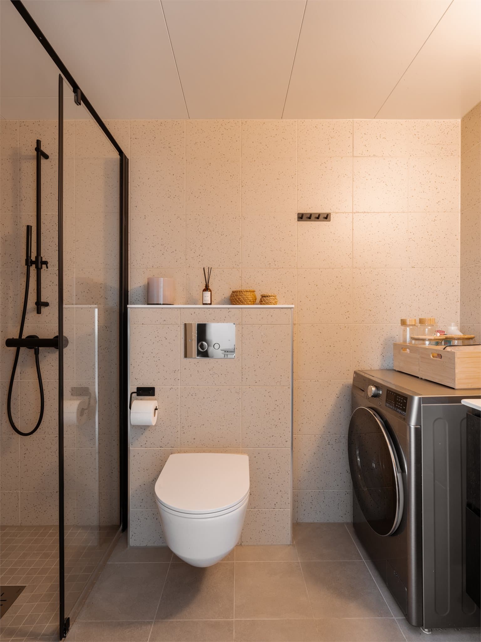 Et lekkert baderom med fine fliser, gulvvarme, dusjnisje, og god plass til oppbevaring.