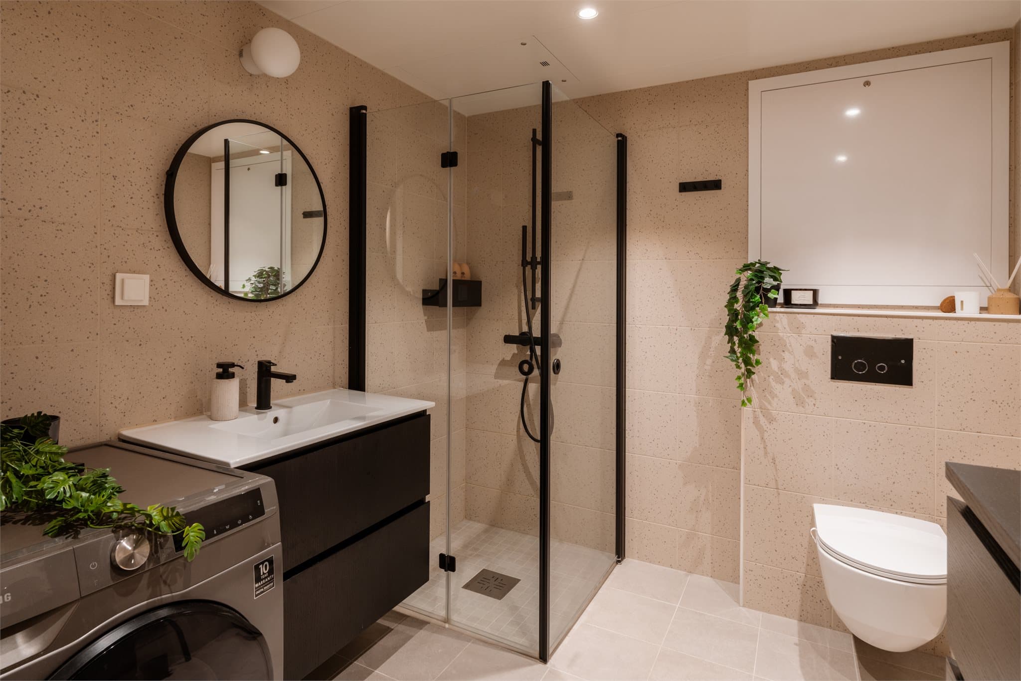 Et rålekkert baderom med delikate flisvalg og opplegg for både vaskemaskin og tørketrommel.