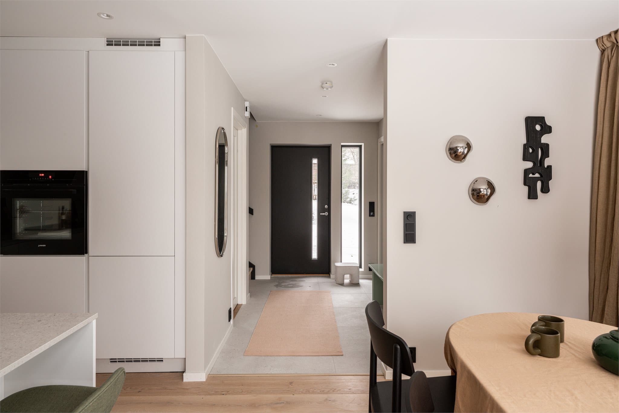 Velkommen inn i en lys entré med lyse flater og mørke detaljer som setter tonen for boligen.