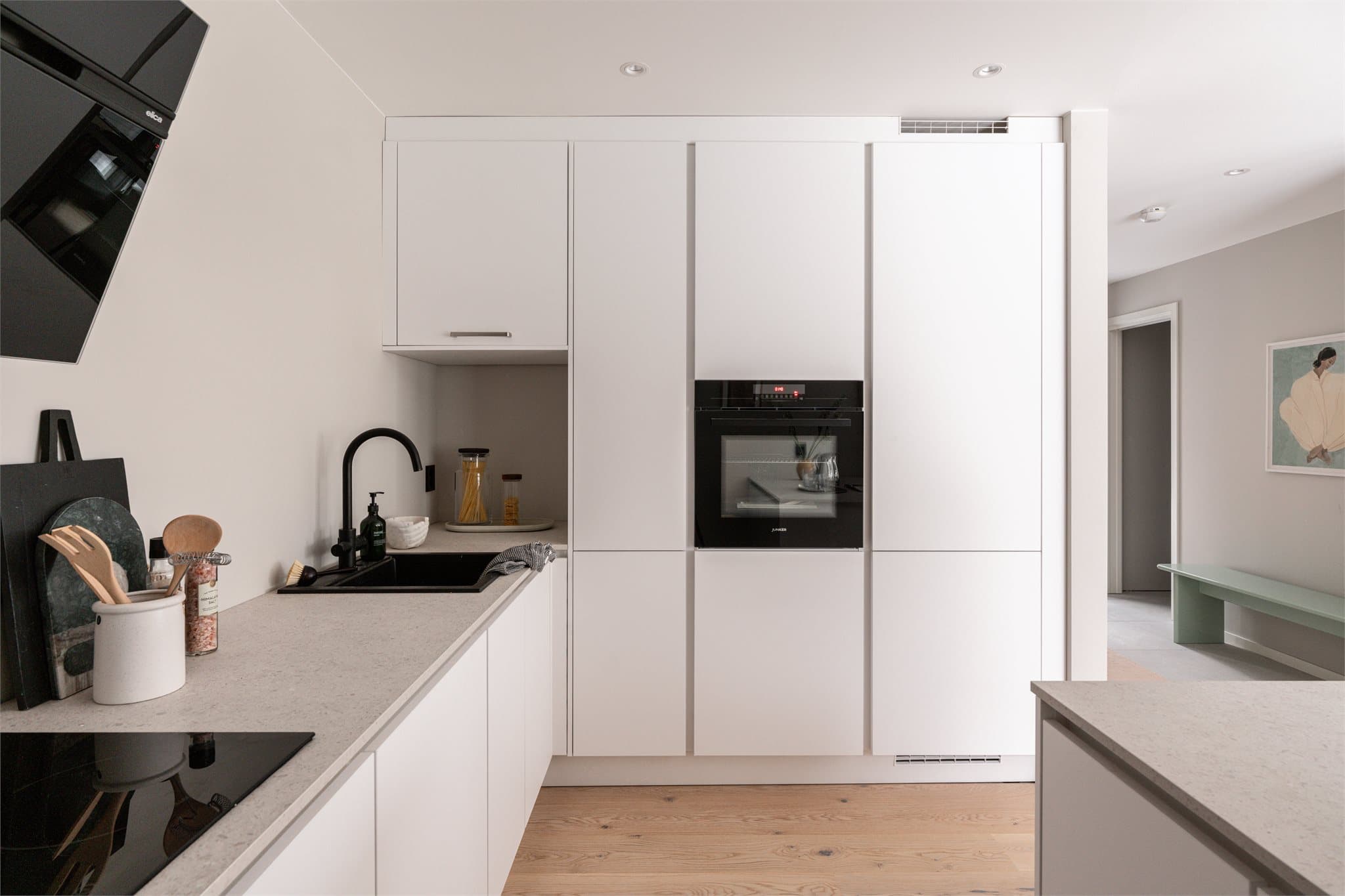 Stilrent grepsløst design med integrerte hvitevarer og sorte detaljer.