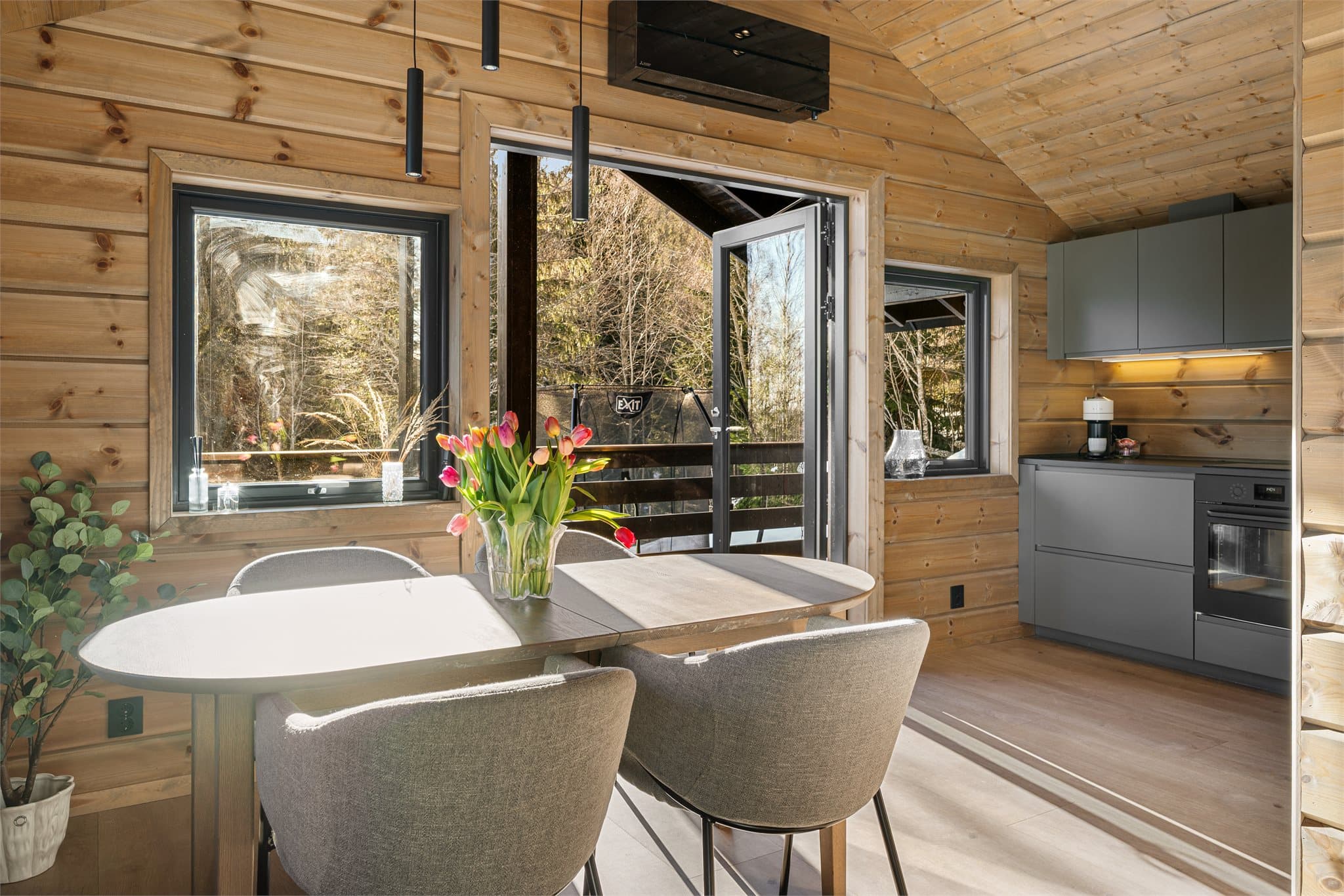 Over den tofløyede balkongdøren, mellom spisestue og kjøkken, er det montert en moderne sort varmepumpe som både glir stilrent inn i interiøret og bidrar til et behagelig inneklima året rundt.