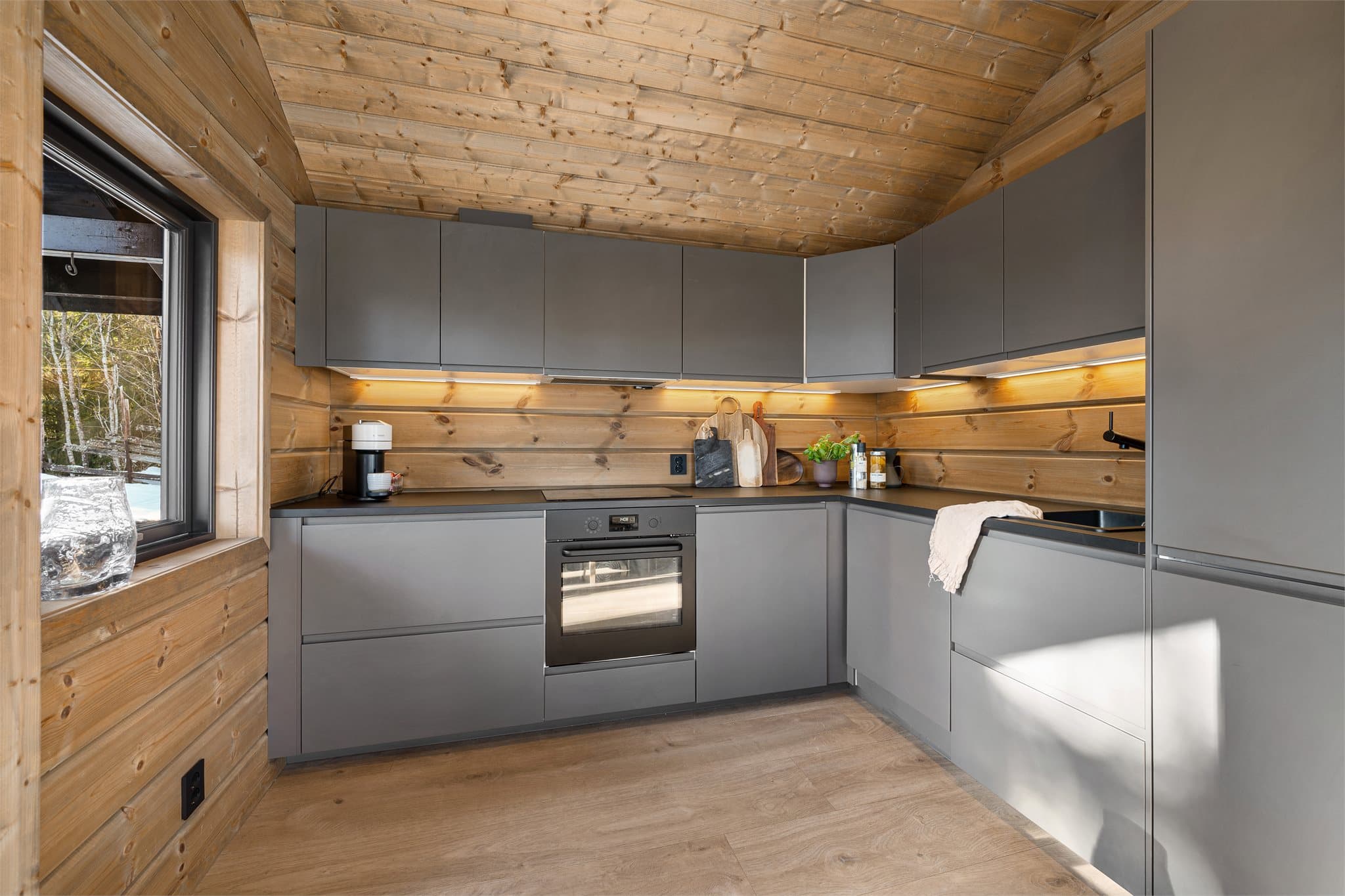 Den robuste laminatbenkeplaten gir gode og romslige arbeidsflater, perfekt for både matlaging og hyggelige måltidsforberedelser. Den mørke komposittvasken kombinert med sort armatur gir et moderne og eksklusivt preg som står flott til de rene linjene.