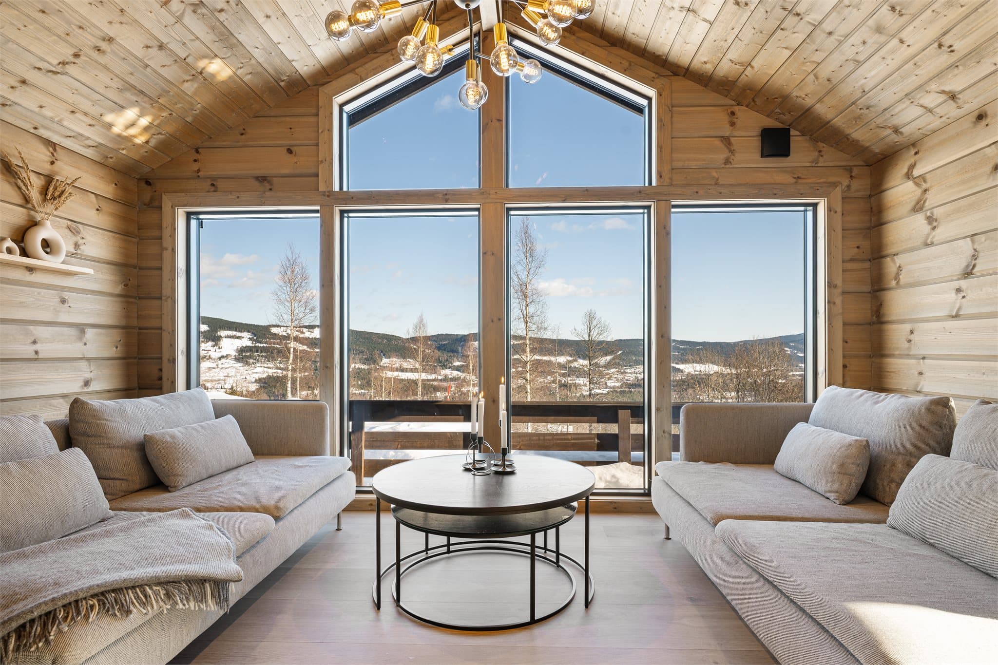 Fra stuen åpner det karakteristiske utstikket seg mot naturen og skaper en flott utsiktssone hvor store glassflater slipper landskapet helt inn i rommet. Her bader stuen i naturlig lys, samtidig som du kan nyte den rolige utsikten mot skog og åsrygger.