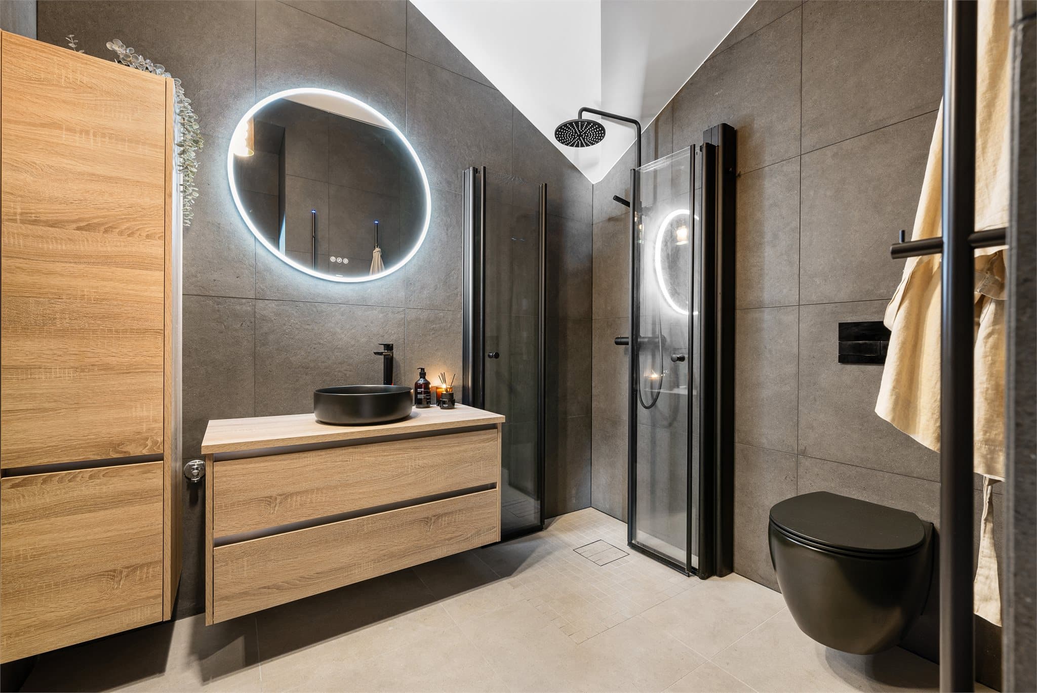 Baderommet fremstår som lekkert, moderne og gjennomført med et stilrent design og høy funksjonalitet. Store 60×60 fliser gir rommet et elegant uttrykk og skaper en følelse av romslighet, mens dusjen med herdet glass og sorte detaljer gir et moderne preg.