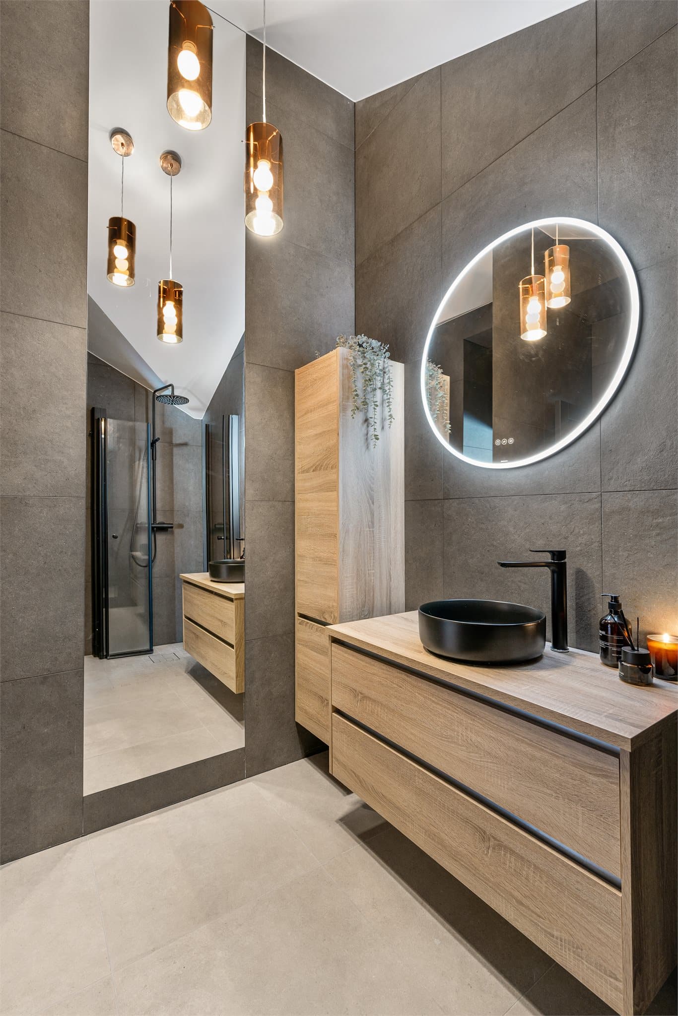 Sorte håndkletørkere på veggen tilfører både praktisk komfort og et sofistikert preg, mens detaljer som herdet glass med sorte profiler og downlights i himlingen fullfører det moderne og luksuriøse uttrykket.