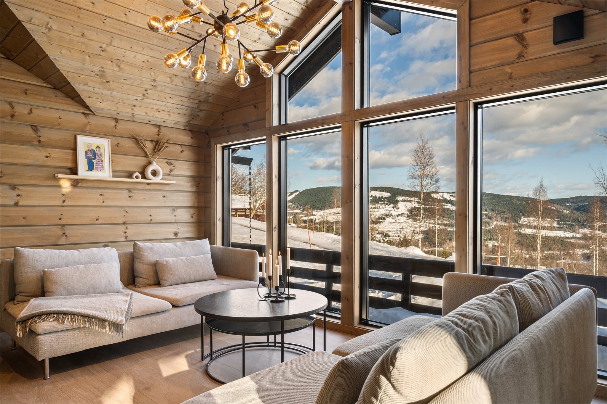 De mange vinduene gir en nærhet til naturen året rundt – enten snøen faller stille utenfor eller solen varmer over landskapet. Resultatet er en lys, luftig og særdeles hyggelig stue hvor inne- og utefølelsen smelter sammen.