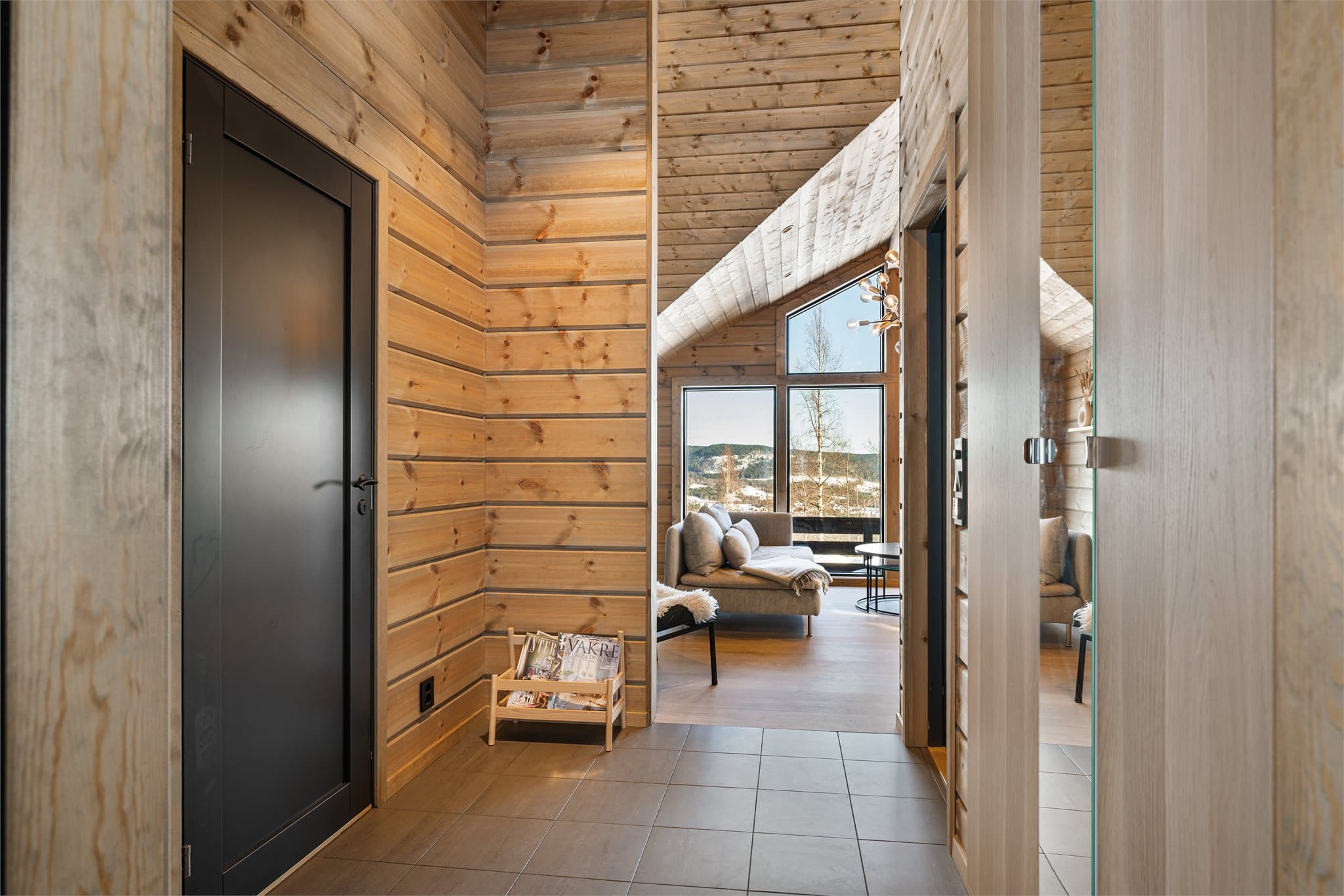 Velkommen inn! Entréen ønsker deg velkommen med en stilren og lun atmosfære – her møtes moderne fjellhyttepreg og praktiske løsninger. Gulvet er belagt med mørke fliser med behagelig gulvvarme, perfekt etter en dag ute i frisk fjelluft.