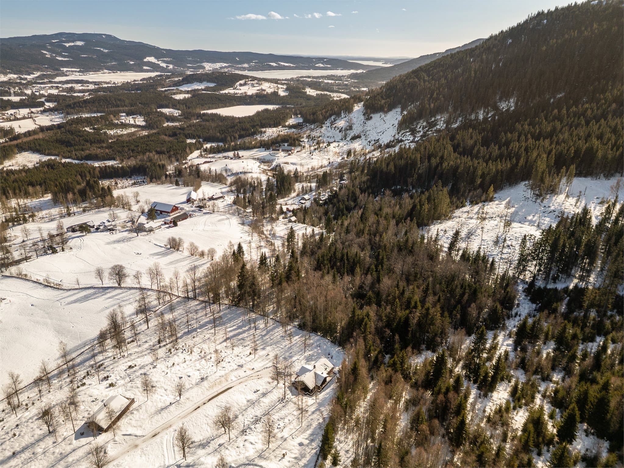 Eiendommen ligger idyllisk til i et rolig og naturskjønt landskap, omgitt av myke åser, skogkledde høyder og vakker norsk natur. Fra luften ser man tydelig hvordan hyttene ligger luftig og harmonisk plassert i terrenget.