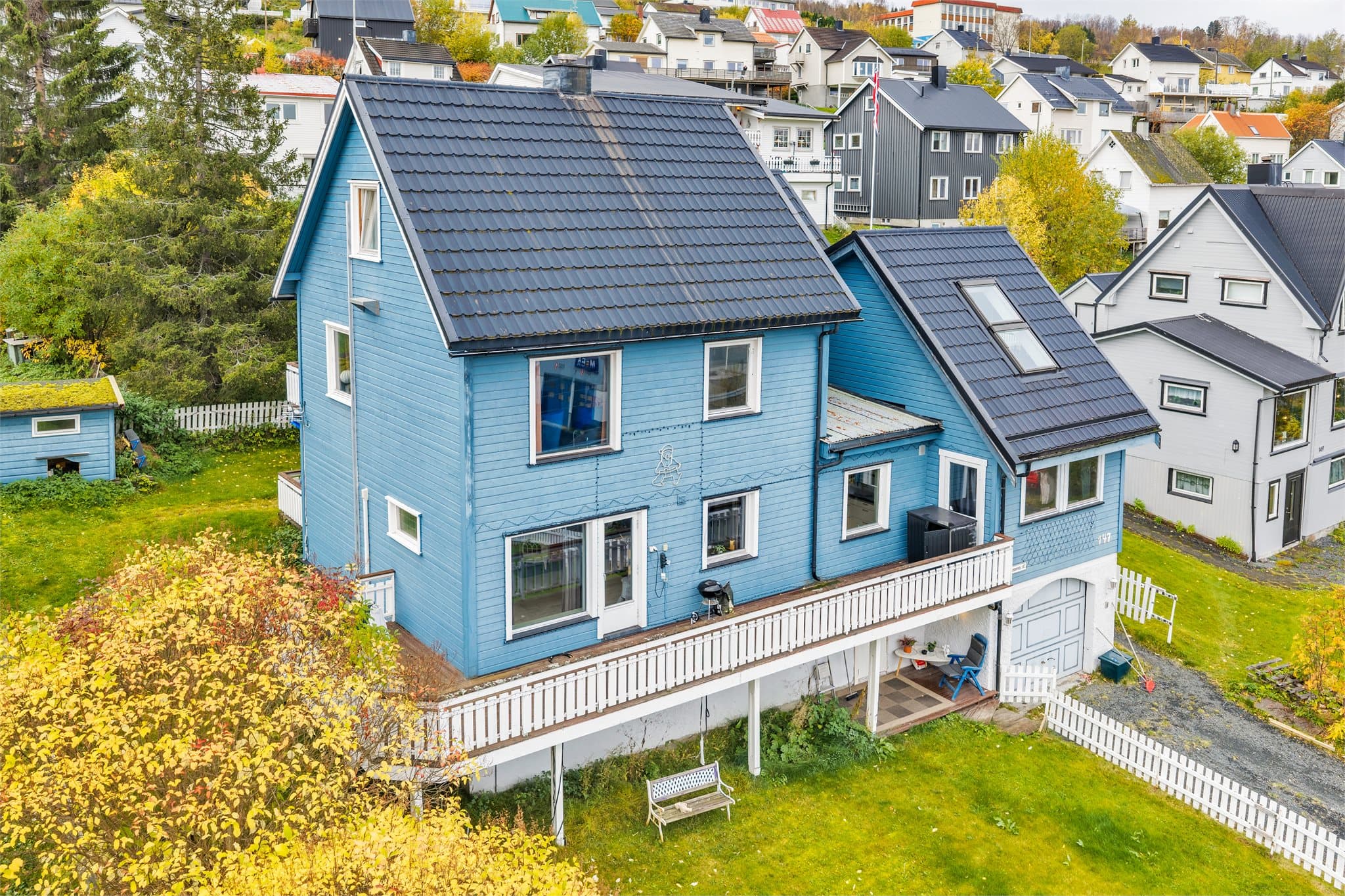 Tomten er opparbeidet med gressplen, hvitt stakittgjerde og gruset adkomst.