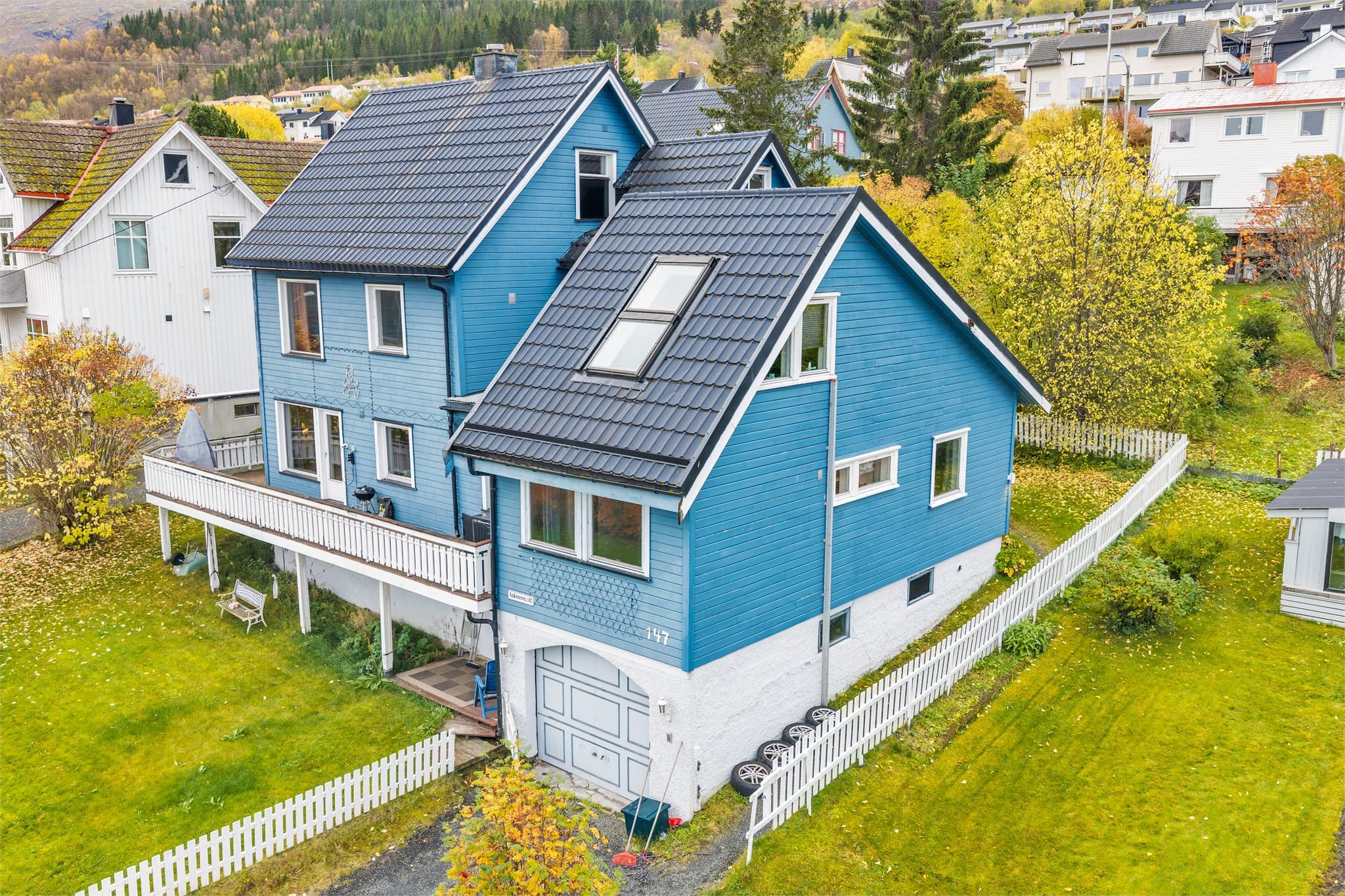 Boligen har sammenbygd garasje på sokkelnivå og romslig innkjørsel.