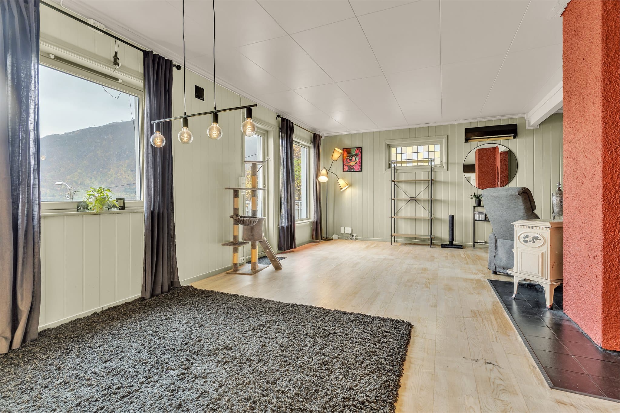 Stuen i 1. etasje har vedovn, plass til sittegruppe og store vindusflater mot fjorden.