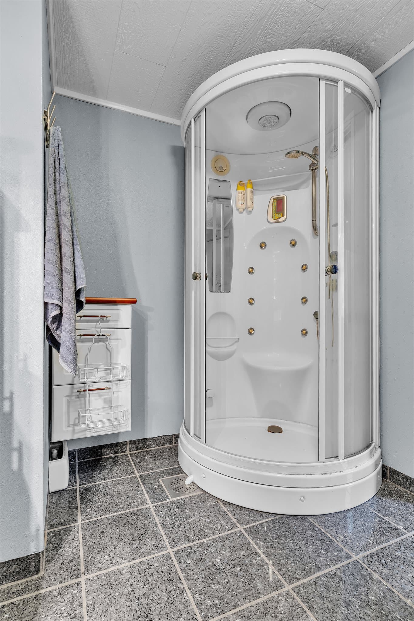 Badet i 2. etasje har flislagt gulv, malte strieplater på vegger og buet dusjkabinett.