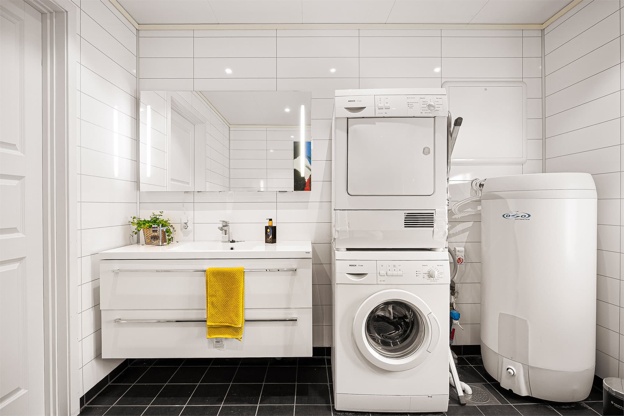 - Badet er innredet med heldekkende servant, speil med belysning, vegghengt toalett, innfellbart dusjhjørne i glass og opplegg for vaskemaskin/tørketrommel -