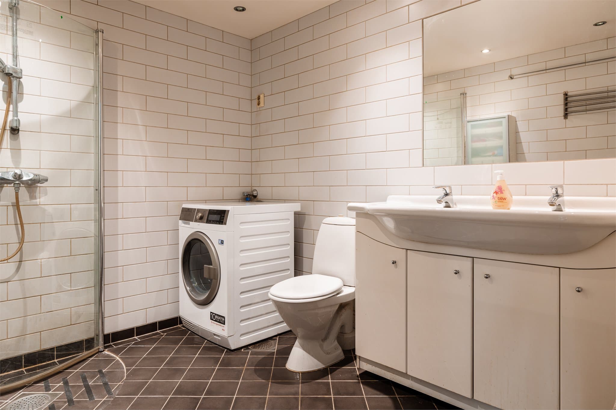 Et lyst og romslig baderom med flislagte overflater og varme i gulvene.