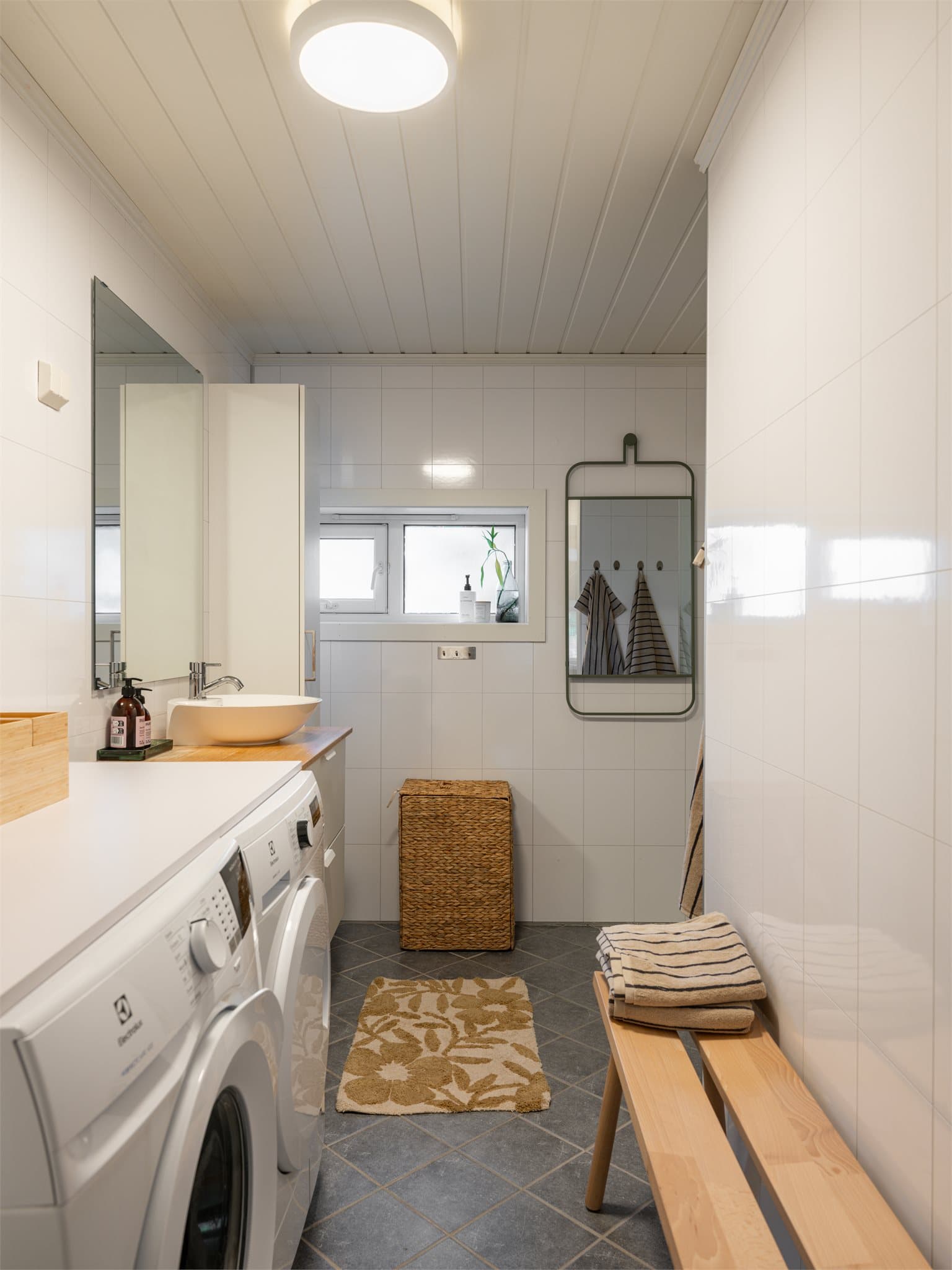 Badet har flislagt gulv med elektriske varmekabler, våtromsplater på veggene og panel i taket.