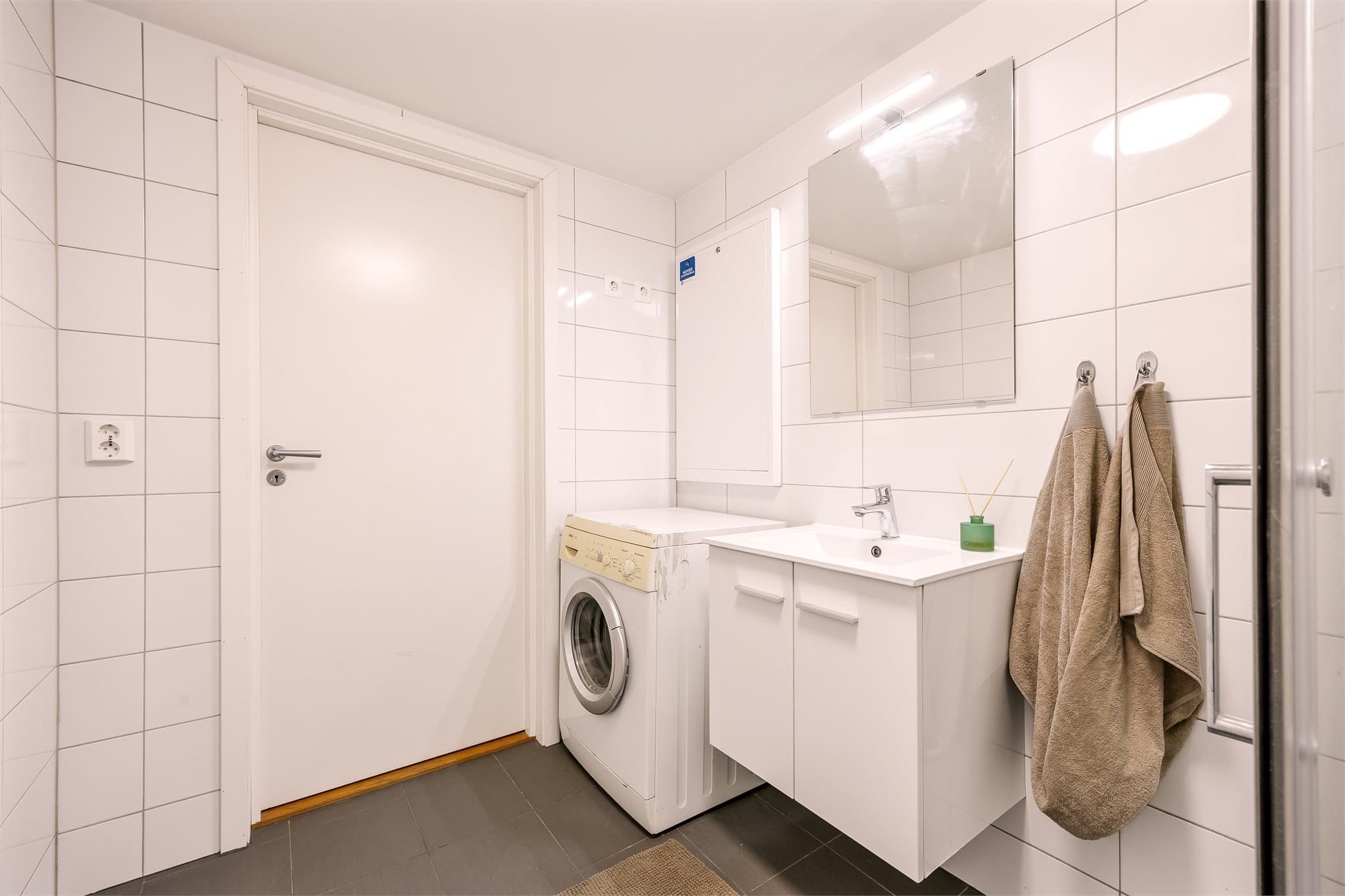 Badet er innredet med helservant på skapseksjon, dusjhjørne og vegghengt toalett.