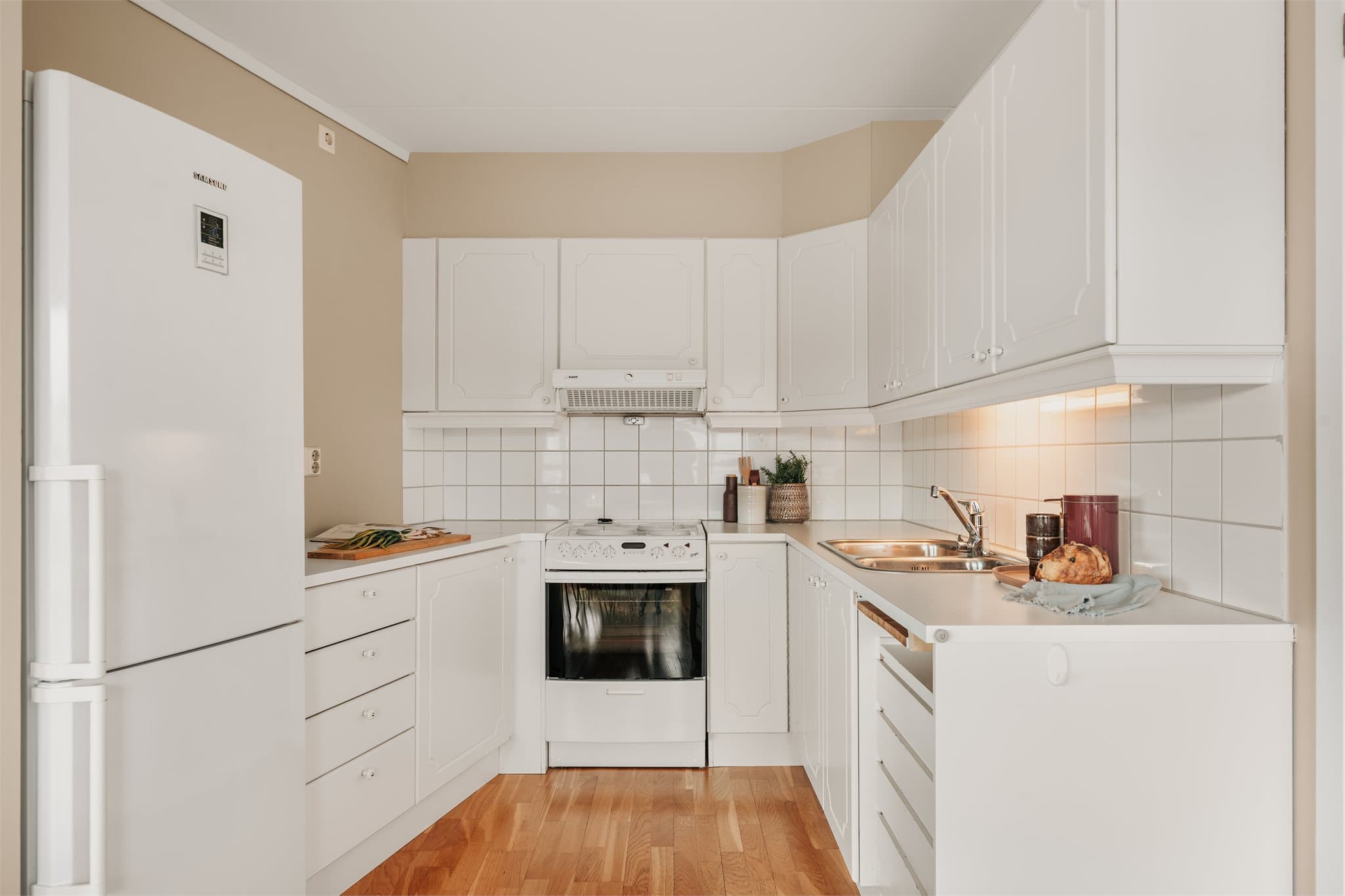 Kjøkkenet har en praktisk innredning fra byggeårene med fabrikklakkerte fronter i glatt utførelse. Benkeplaten er i laminat og har nedfelt oppvaskkum i rustfritt stål. Veggene over benkeplaten er flislagt.