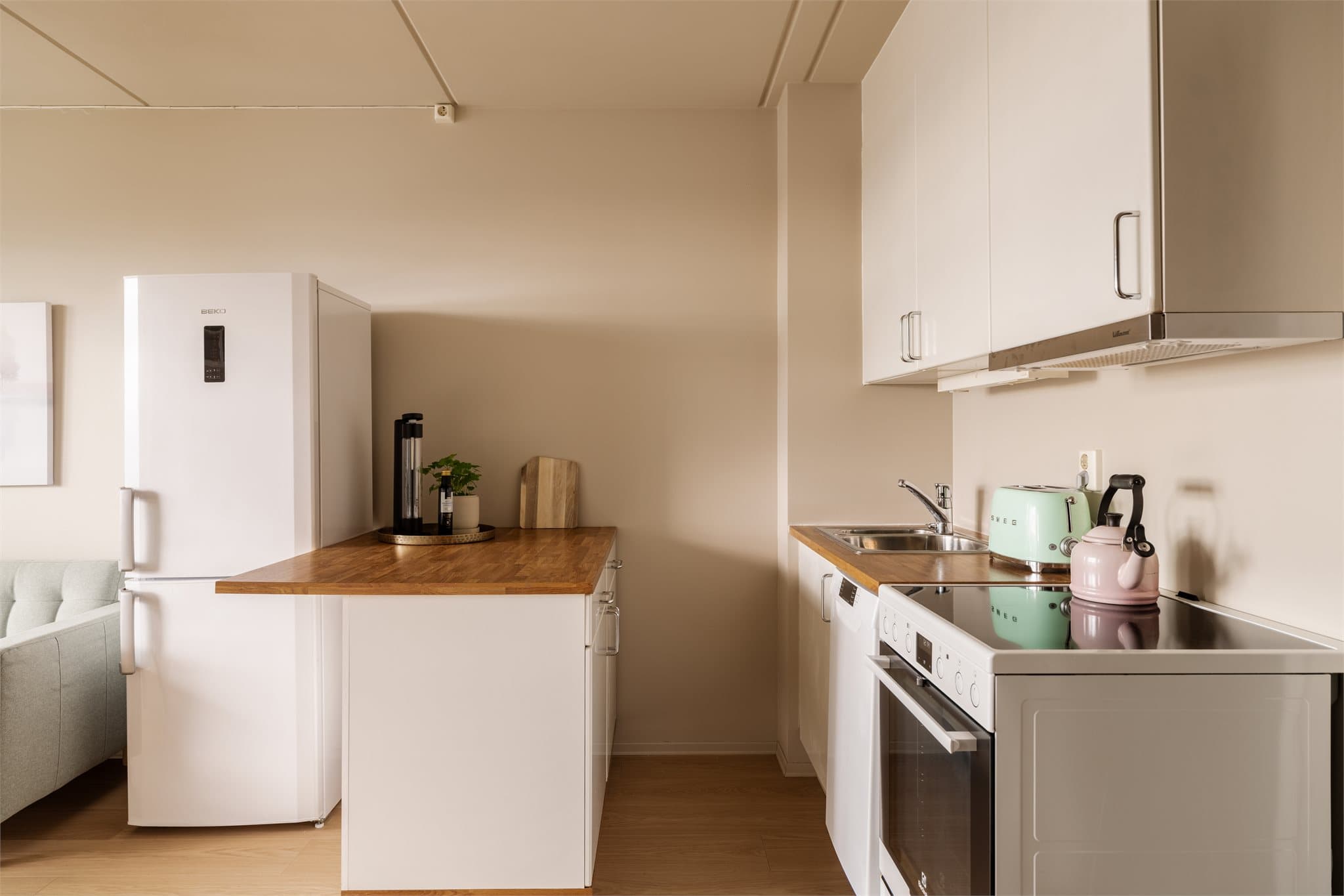 Innredningen bestående av benkeplate i laminat, frittstående oppvaskmaskin (smal type), platetopp, stekeovn og frittstående kjøl/frys.
