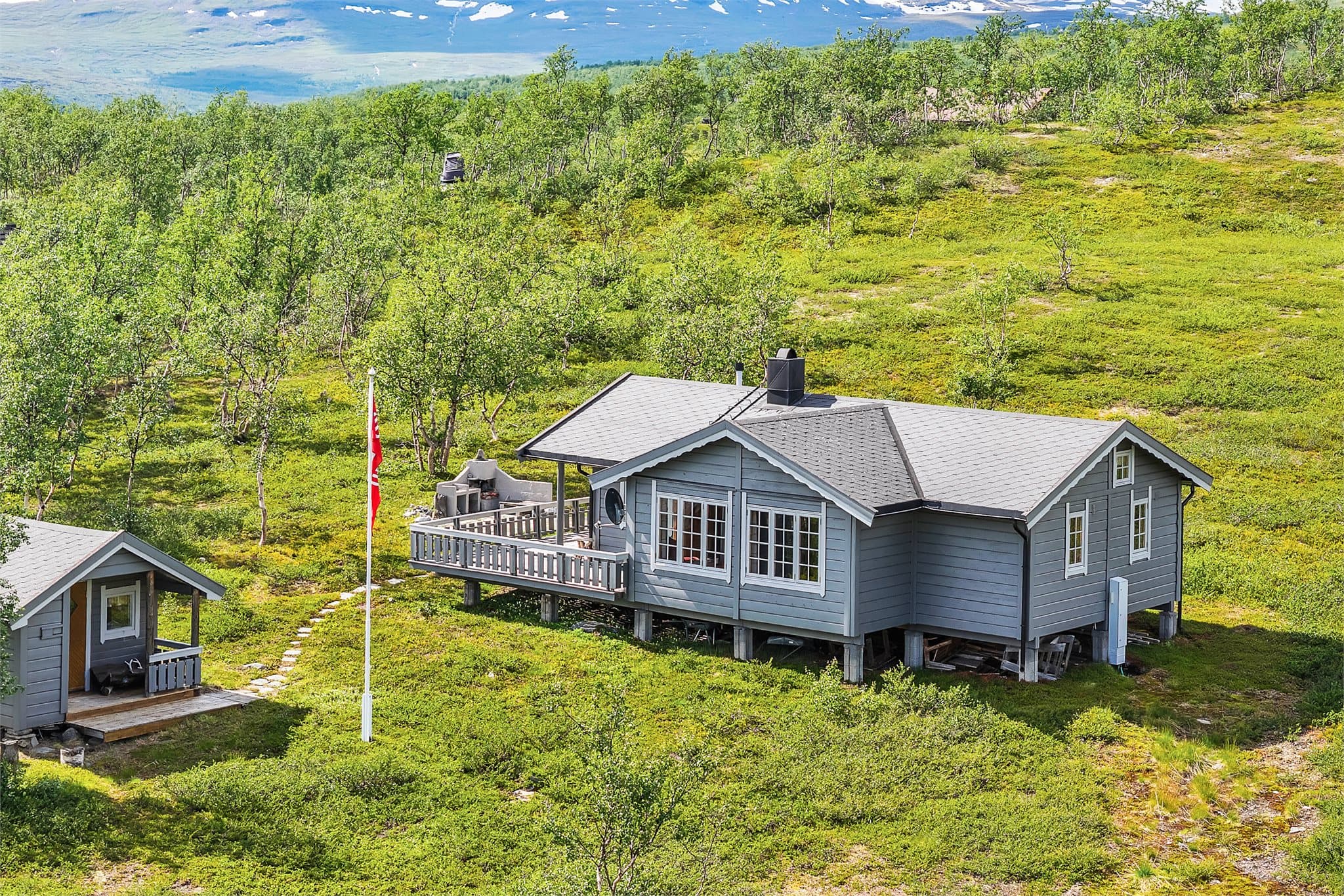 Eiendommen består av fritidsbolig og et separat uthus, plassert på en lett hellende naturtomt.