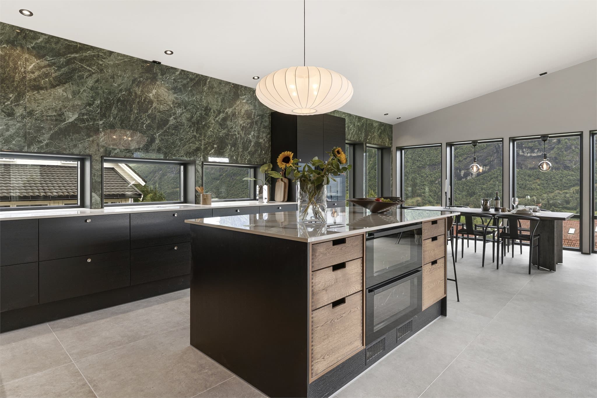 Kjøkkenet er spesialtilpasset fra JKE og fremstår som et naturlig samlingspunkt i boligen. Innredningen har beislakkerte finerfronter og benkeplate i Dekton, hvor samme materiale er videreført inn i vindusnisjen som en gjennomført detalj.