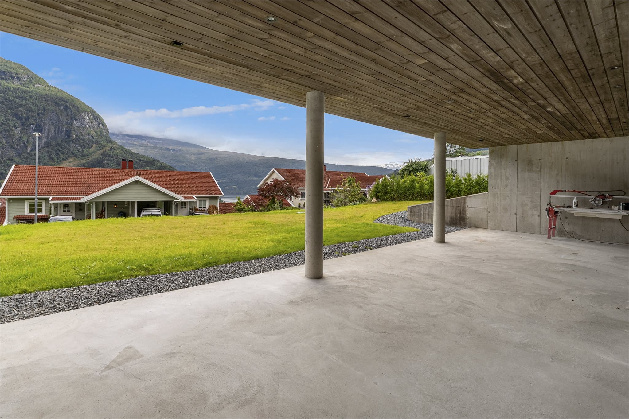 Fra både stuen og ett av soverommene er det direkte utgang til en overbygd markterrasse i betong. Arealet gir en lun og skjermet uteplass på bakkenivå.