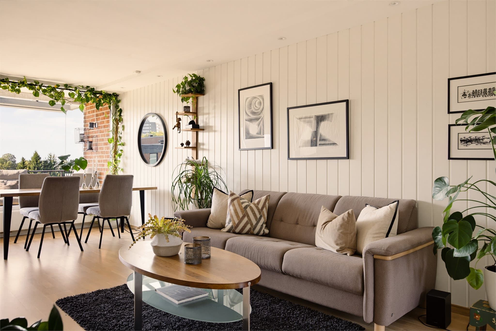Stuen har parkett på gulvet som er gjennomgående lik i alle rom, en vegg med lysmalt trepanel og downlights fra 2023 som bidrar til en lun og moderne atmosfære.