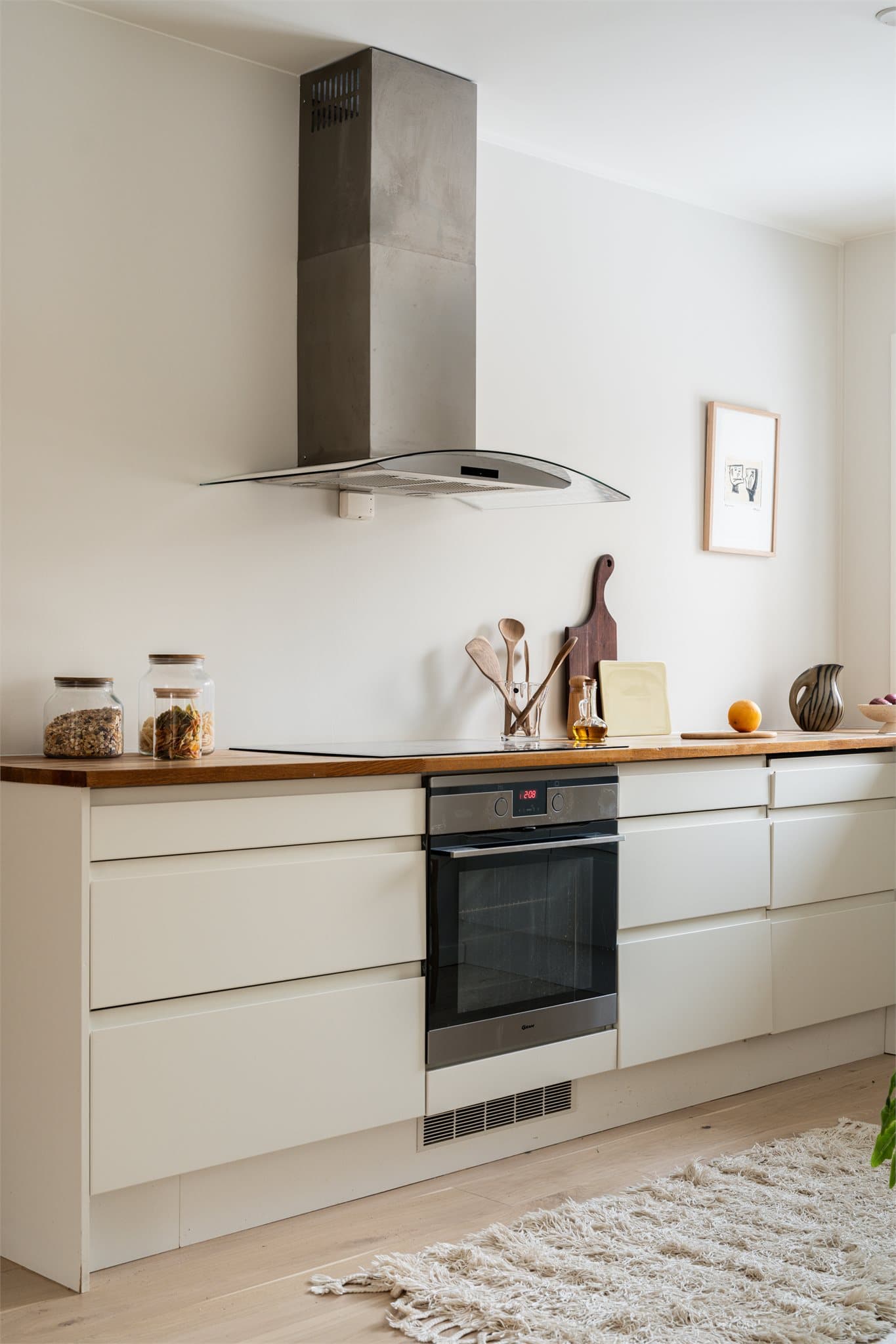 Kjøkkenet har glatte fronter og benkeplate av heltre, med integrert frys/kjøleskap, oppvaskmaskin, vaskemaskin, platetopp, stekeovn, vannstopper og komfyrvakt.