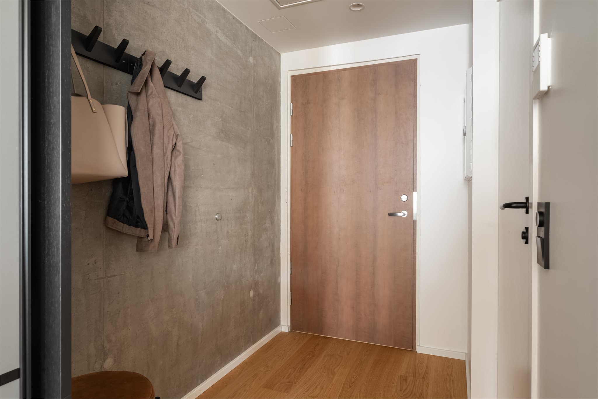 Innbydende gang med industrielt inspirert betongvegg som setter et tøft preg på rommet.