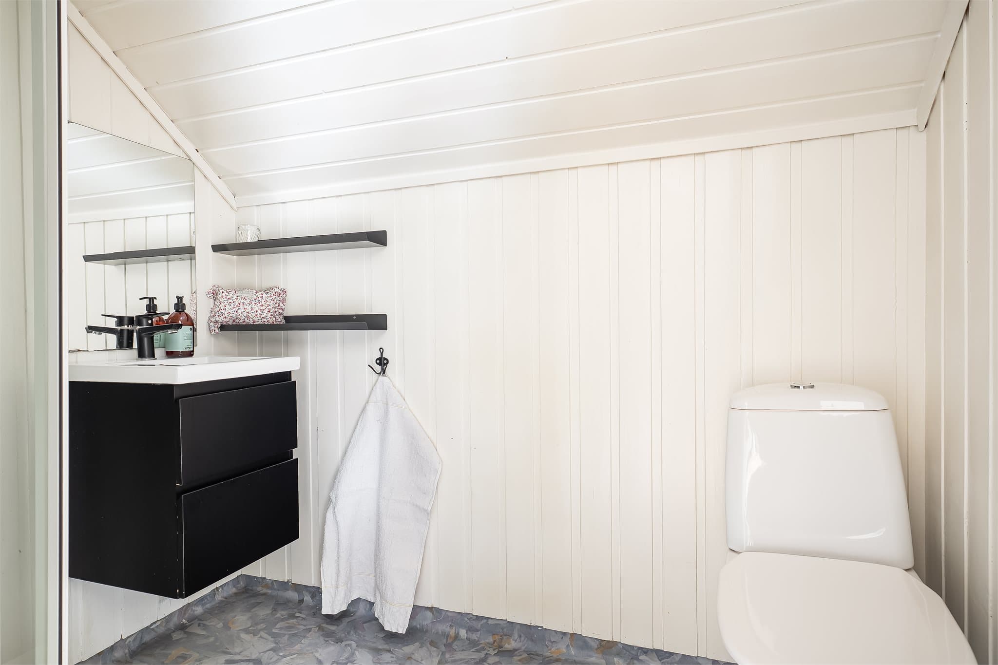 Badet er utstyrt med vegghengt servantinnredning, speil, toalett og dusjkabinett.