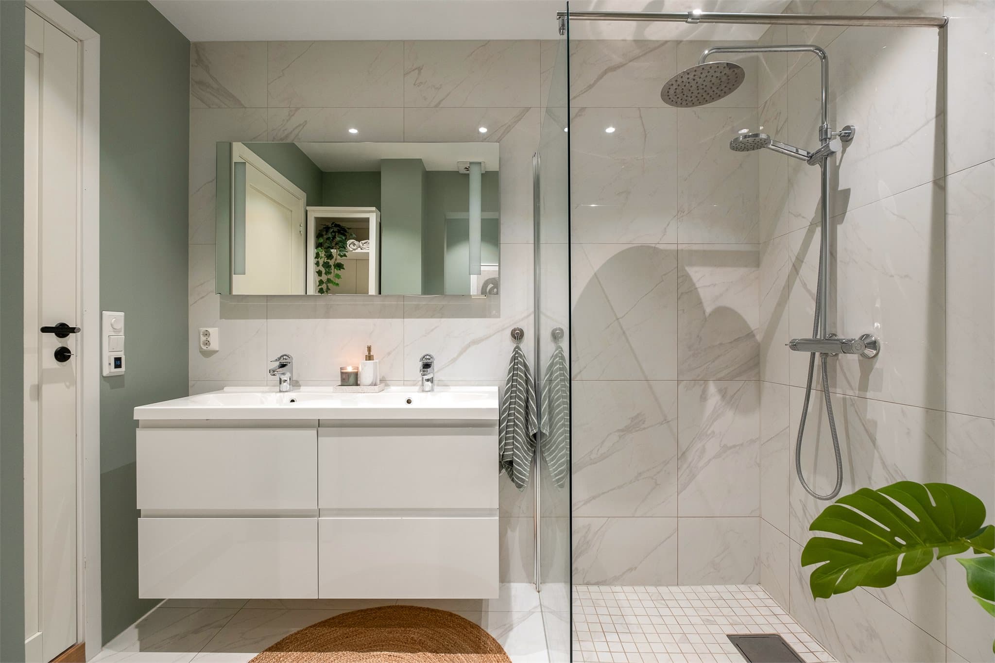 Boligen har et delikat baderom som følger leilighetens moderne stil med store, lyse fliser og downlights i tak.