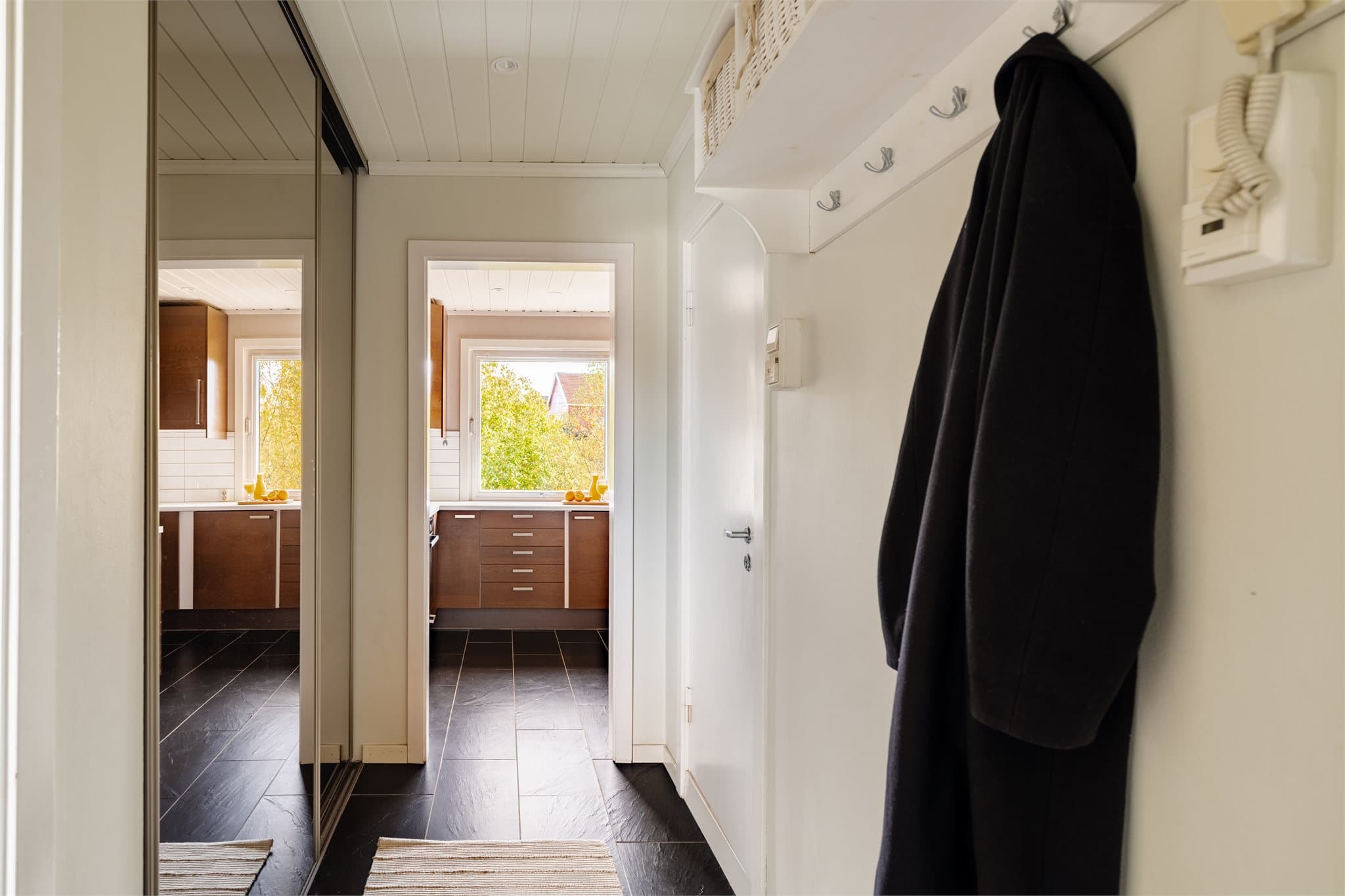 Leiligheten har en innbydende entré med plass til å henge fra seg yttertøy og sette fra seg sko.