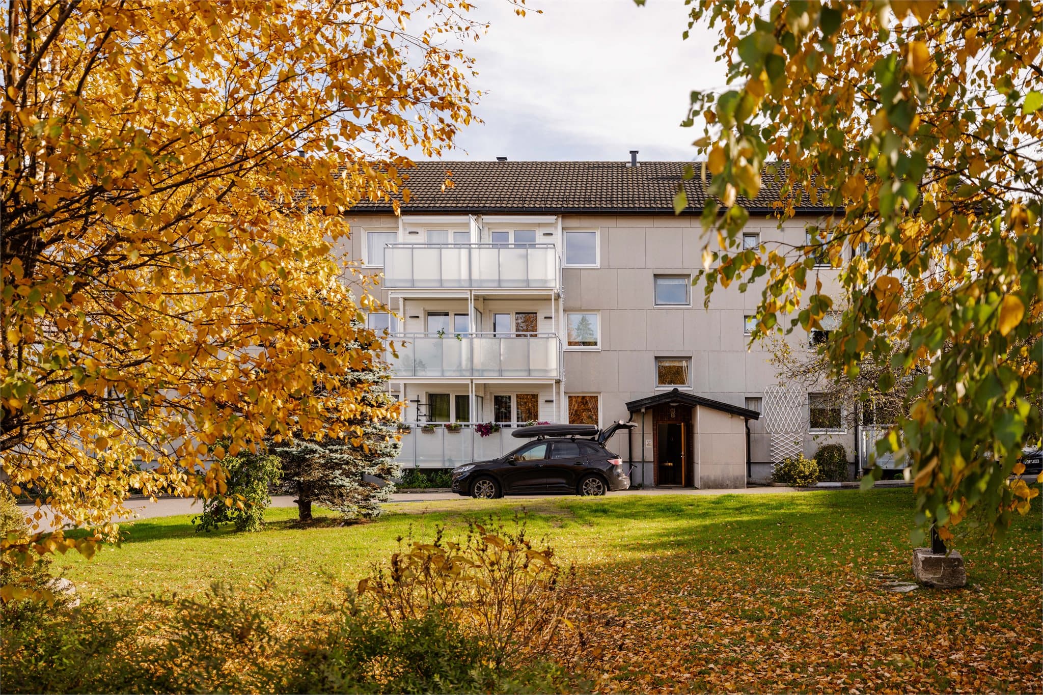 Fasade og inngangsparti. Utenfor boligen ligger pent opparbeidede fellesarealer.