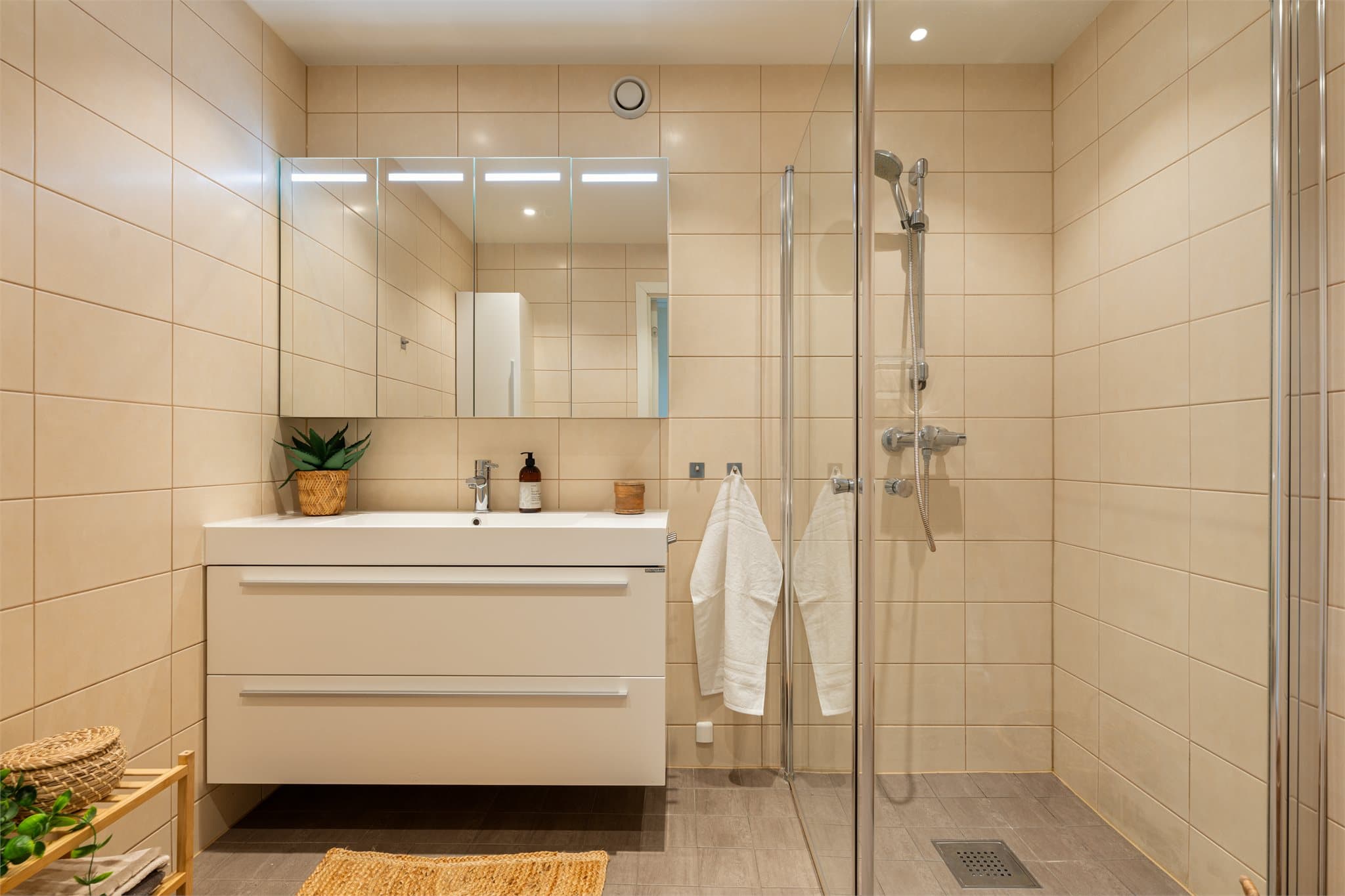 Badet er innredet med servant, skapinnredning og dusj, samt praktisk opplegg for vaskemaskin.