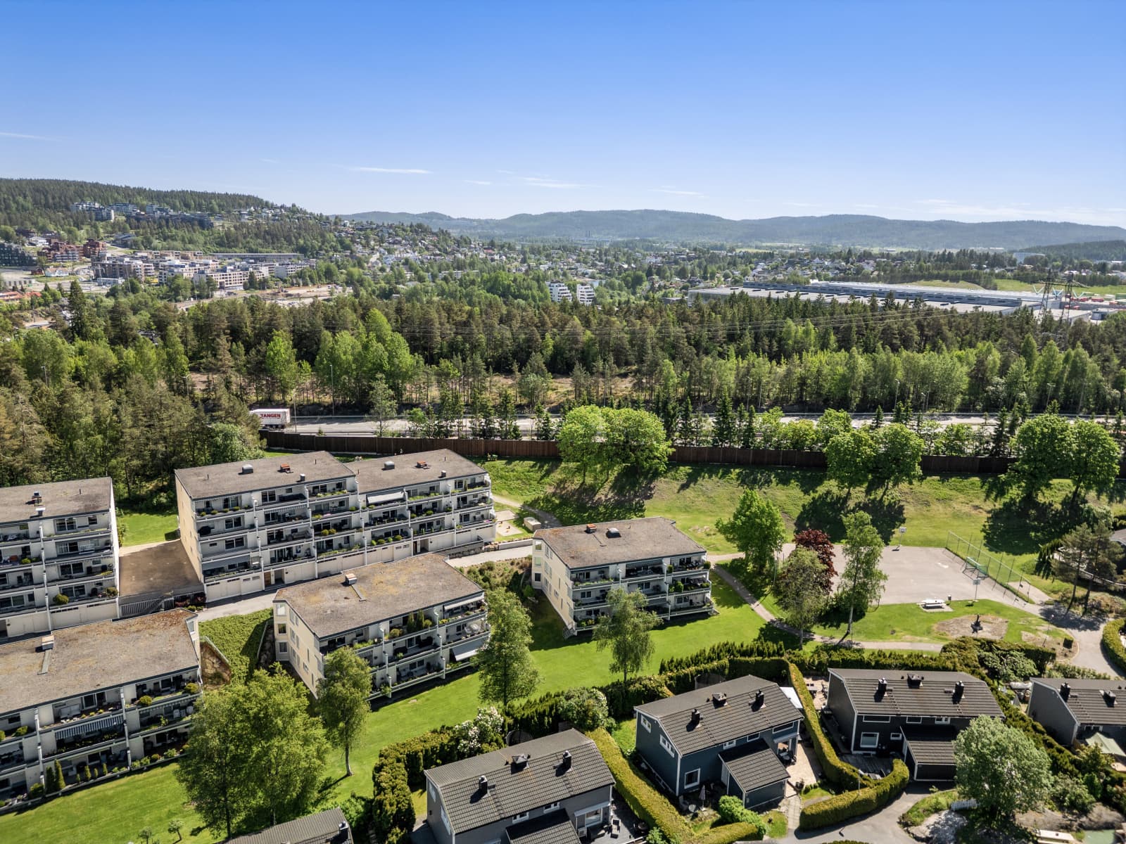 Dronebildene viser borettslagets attraktive plassering med åpne grøntområder, god avstand mellom bebyggelsen og en luftig atmosfære. Her får du følelsen av å bo landlig og fredelig, samtidig som byen aldri er langt unna.