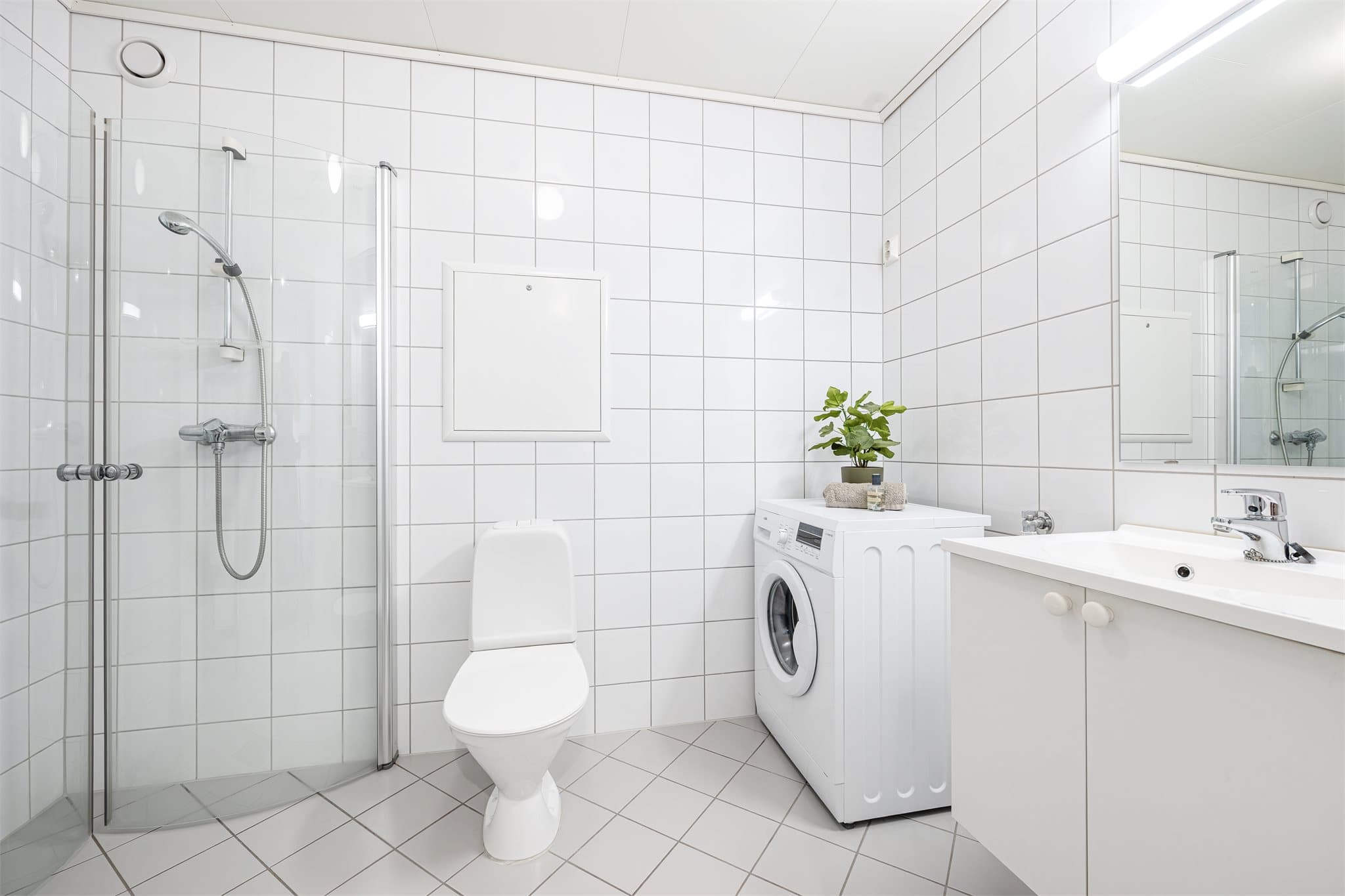 Badet er innredet med dusjhjørne med praktisk innfellbare dusjvegger i herdet glass, klosett samt helservant på skuffeinnredning.