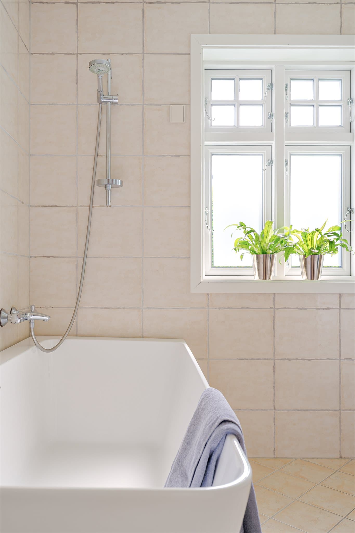 Badet er innredet med badekar med vegghengt dusjgarnityr.