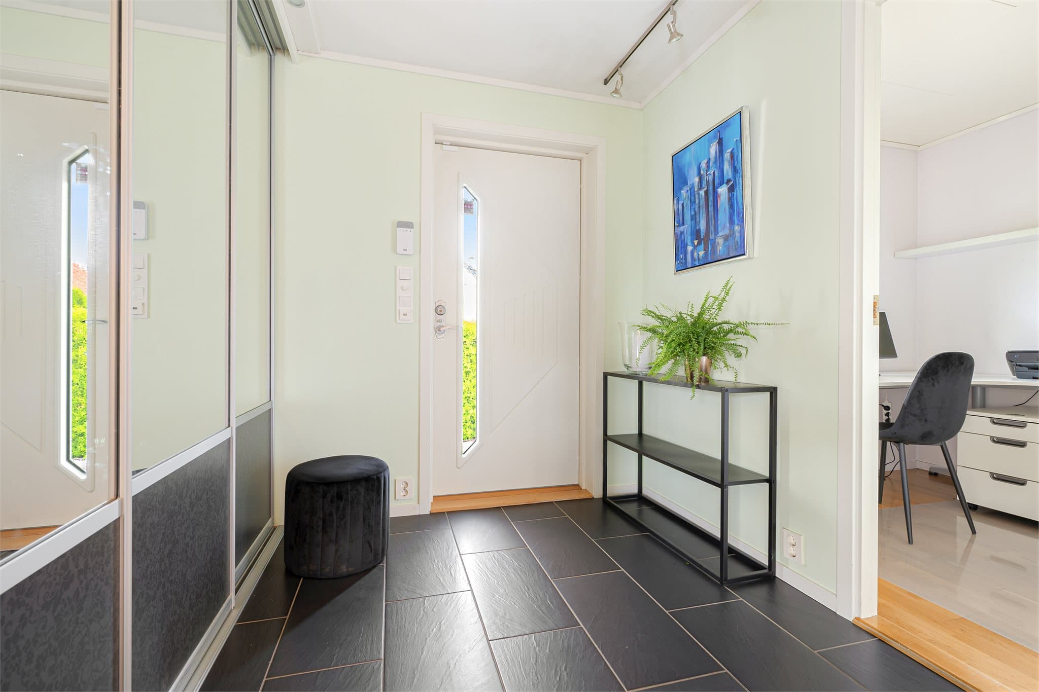 Velkommen inn! Et hyggelig inngangsparti med lite overbygg leder inn til en romslig entré med flislagt gulv og behagelig gulvvarme. Skyvedørsgarderobe med speilfronter gir praktisk oppbevaring og et lyst uttrykk.